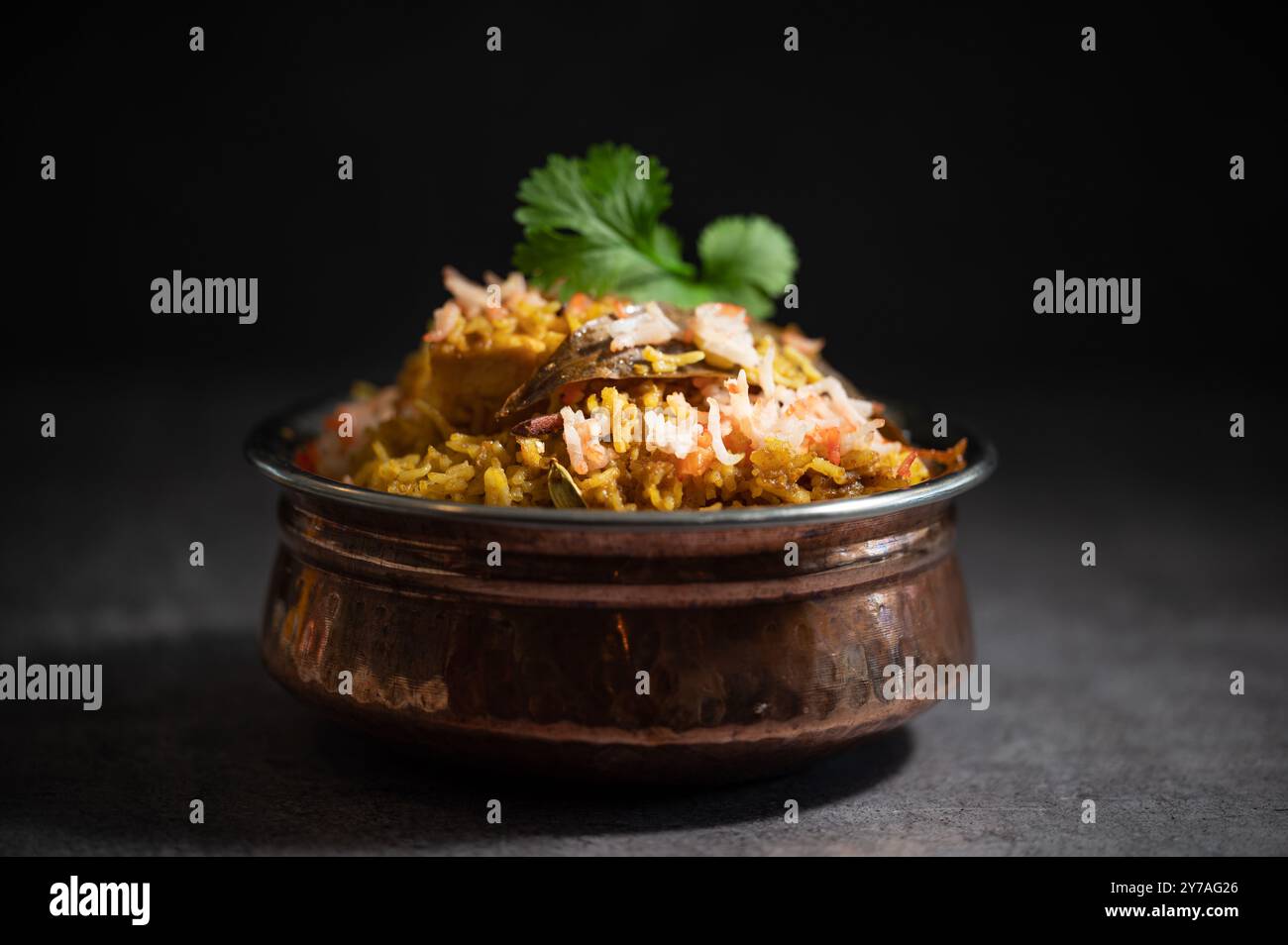 Pulao biryani indiano piccante in ciotola dorata con riso basmati indiano con curry di carne di pollo Ramadan Kareem, Eid. Recipiente da portata in ottone con dorso bianco Foto Stock