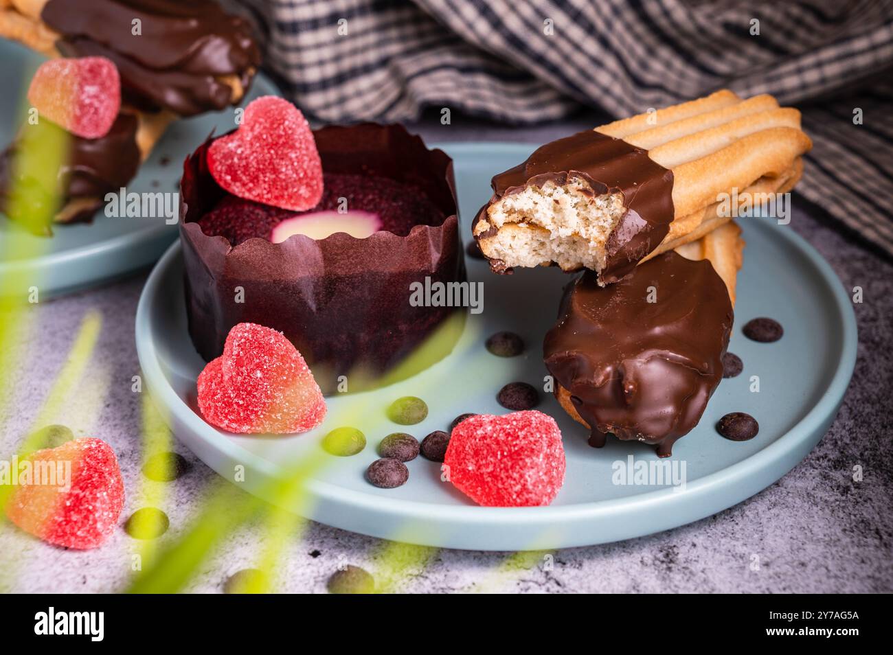Cupcake di San Valentino. Biscotto digestivo rivestito di cioccolato fondente. Dolce delizioso tartufo da dessert e caramelle a forma di cuore su un piatto. Sfondo scuro wi Foto Stock