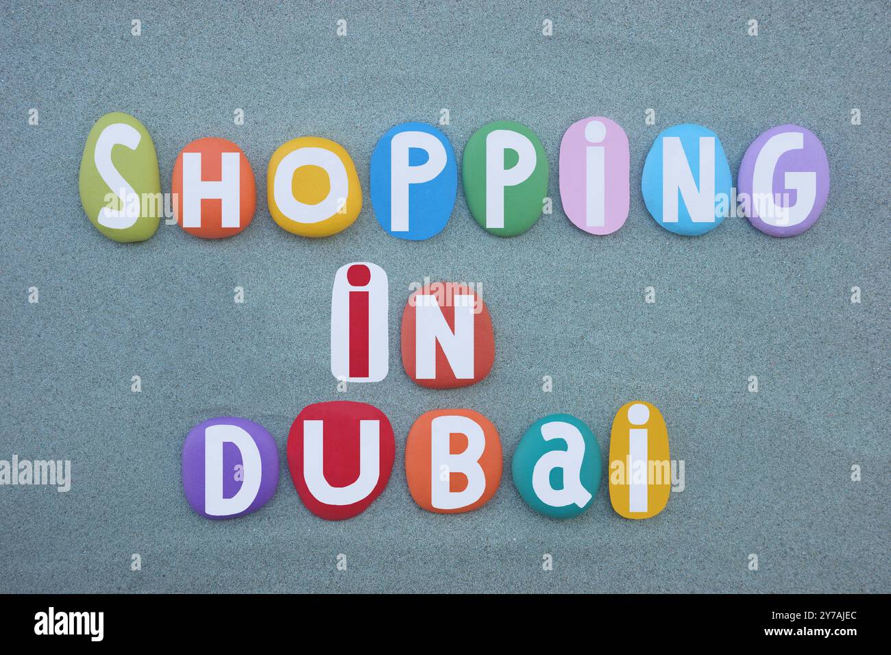 Shopping a Dubai, design creativo con logo composto da lettere in pietra multicolore dipinte a mano su sabbia verde Foto Stock
