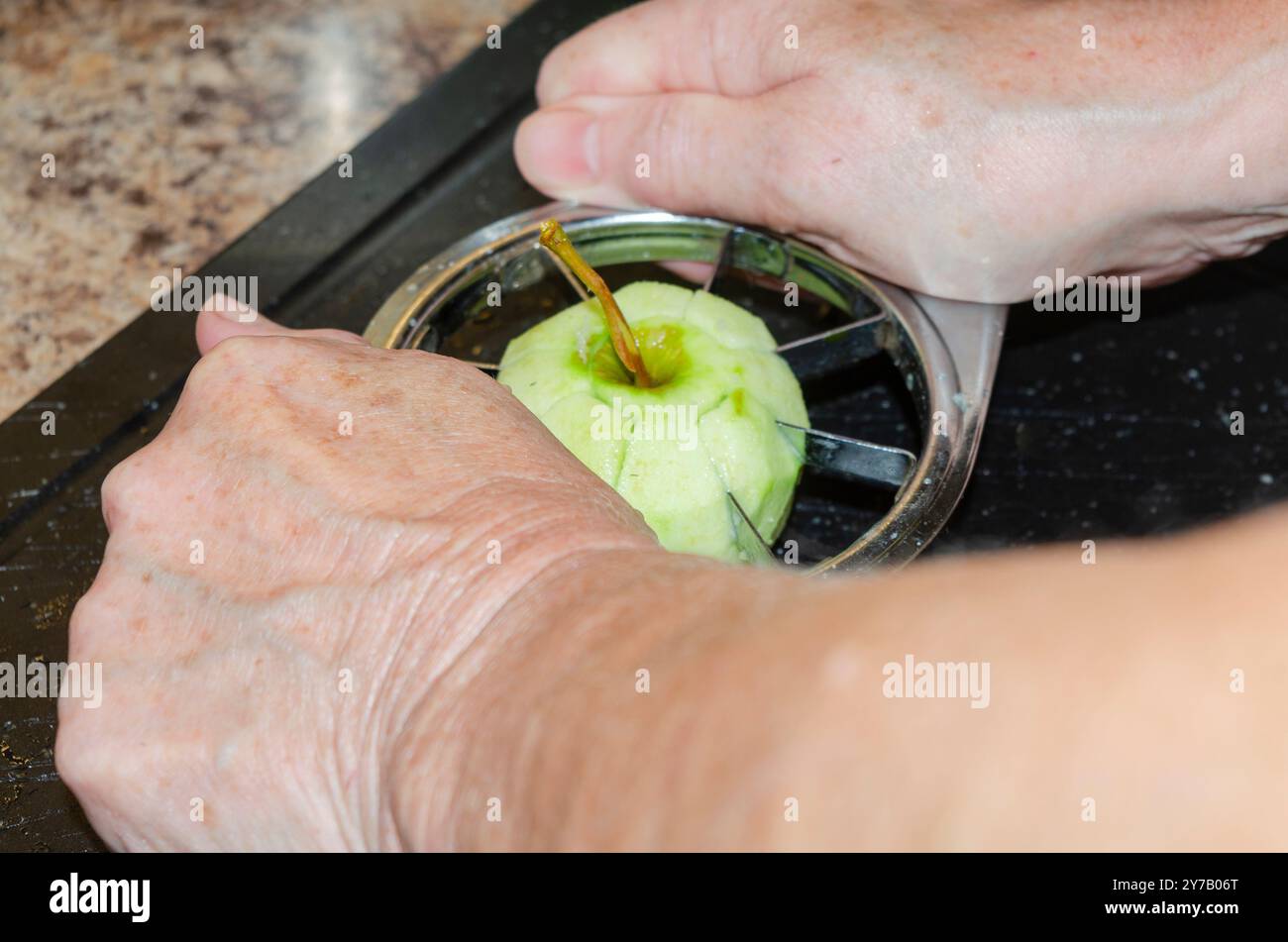 Mani di donna che usano un taglierino per mele per preparare le mele da cucinare Foto Stock