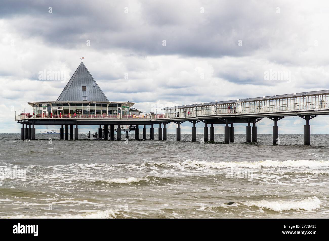 Il padiglione del molo di Heringsdorf si innalza con la sua torre appuntita sopra il Mar Baltico, le onde si infrangono contro i pilastri di sostegno in legno della passerella. Meclemburgo-Pomerania Anteriore, Germania. Foto Stock