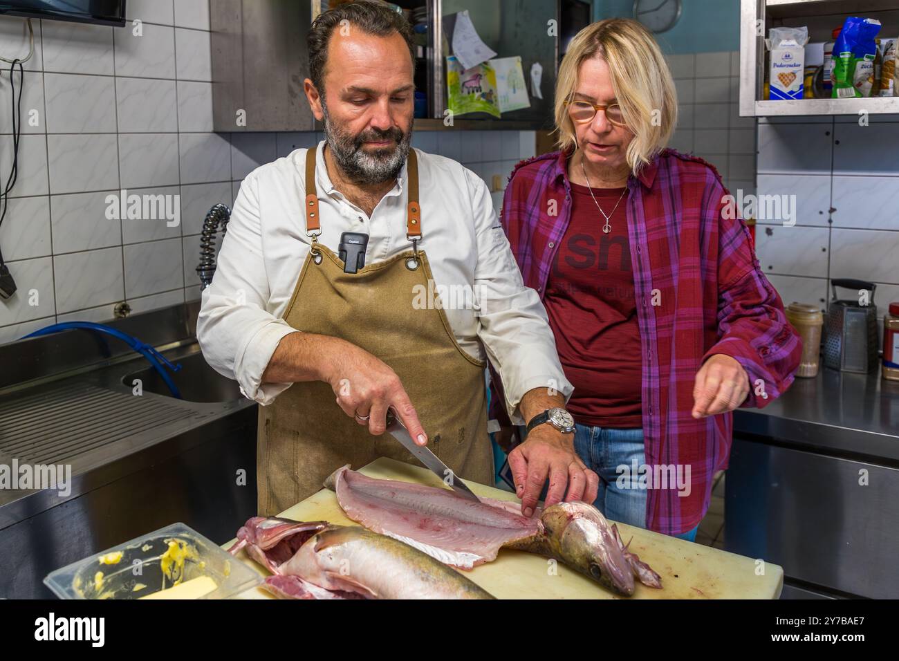 Lo chef René Bobzin prepara il pesce disossato con vari piatti di patate nella cucina del Bauernstube di Bobzin e li presenta personalmente al tavolo della cena. Dewichower Straße, Usedom-Süd, Meclemburgo-Vorpommern, Germania Foto Stock