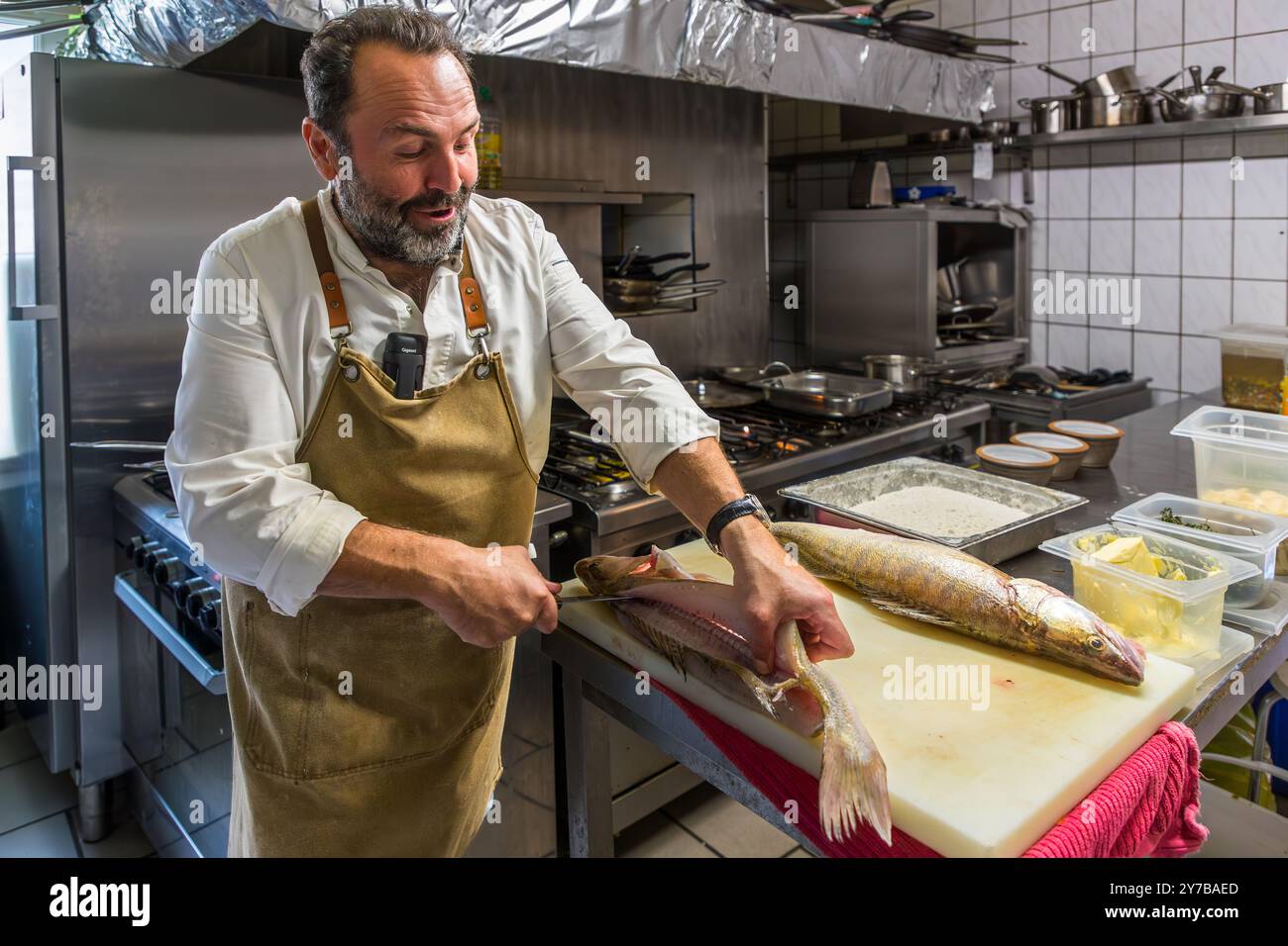 Lo chef René Bobzin prepara il pesce disossato con vari piatti di patate nella cucina del Bauernstube di Bobzin e li presenta personalmente al tavolo della cena. Dewichower Straße, Usedom-Süd, Meclemburgo-Vorpommern, Germania Foto Stock