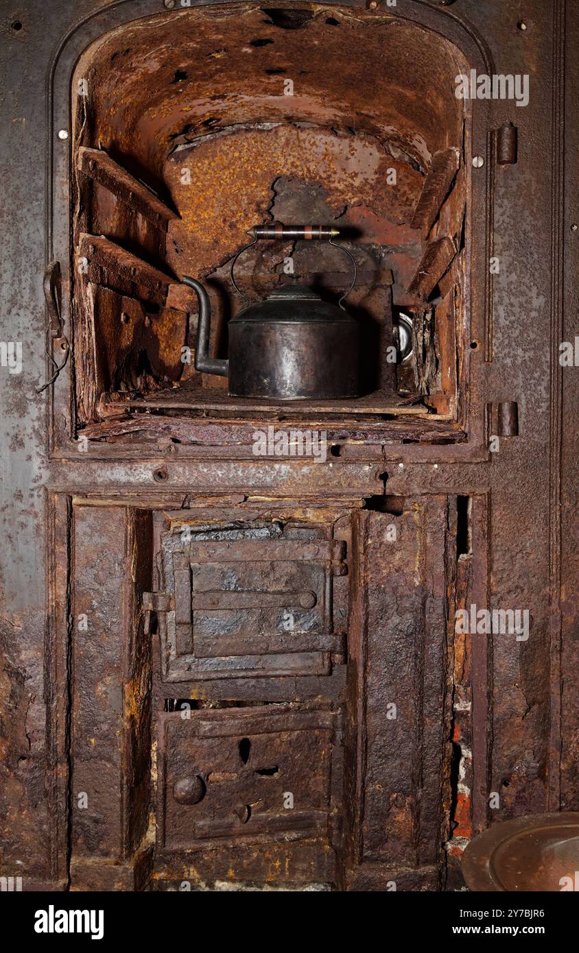 Bollitore in metallo in piedi su un vecchio forno vecchio, usurato, vintage, antico ghisa arrugginito, forno a pane arrugginito, Highcliffe Castle, Regno Unito Foto Stock