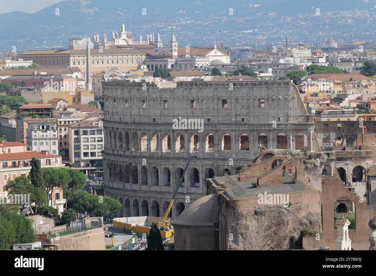 L'antico e iconico Colosseo di Roma (Anfiteatro Flavio) con le sue centinaia di archi e la facciata in travertino decorata, adiacente al foro Romano Foto Stock