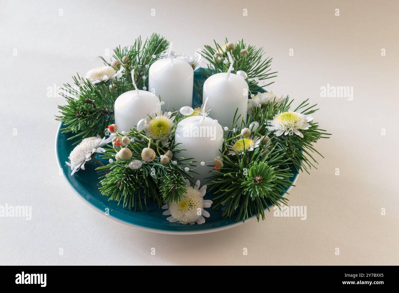 quattro candele bianche dell'avvento, decorazioni a corona con fiori e pino Foto Stock