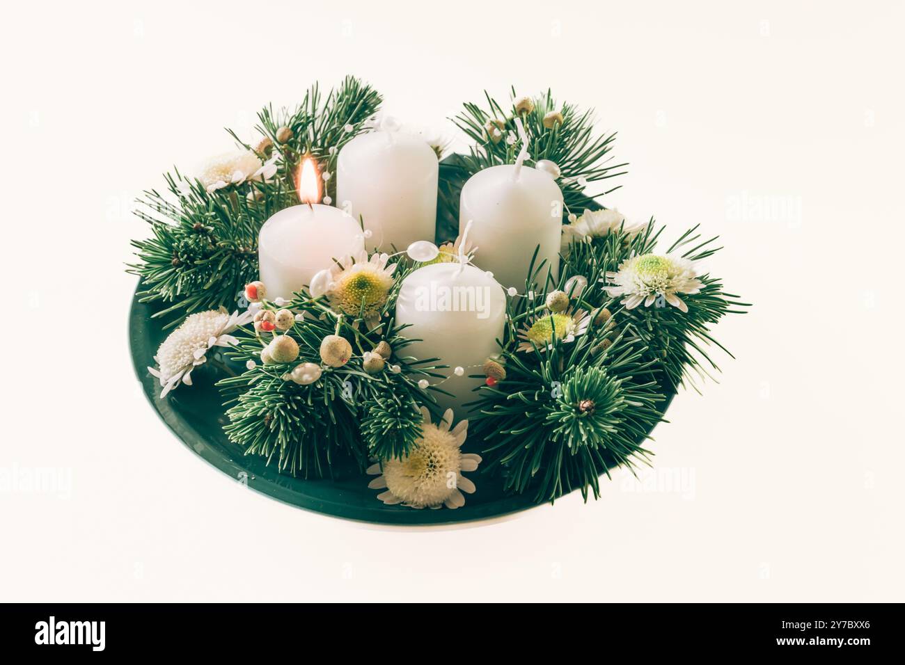 quattro candele bianche dell'avvento, decorazioni a corona con fiori e pini, isolate, candele del primo avvento accese Foto Stock
