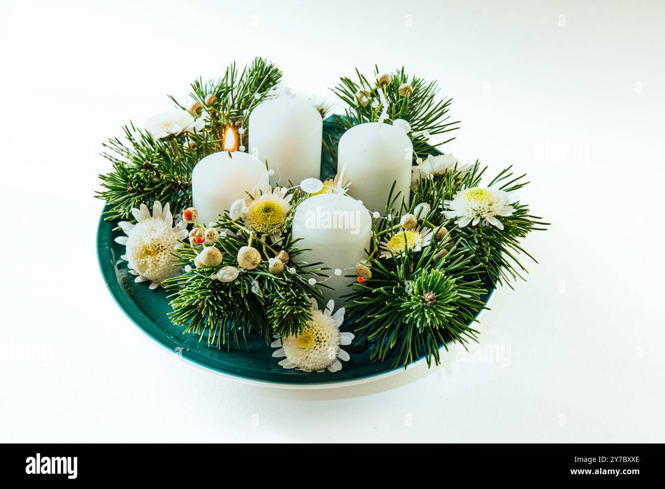 quattro candele bianche dell'avvento, decorazioni a corona con fiori e pini, isolate, candele del primo avvento accese Foto Stock