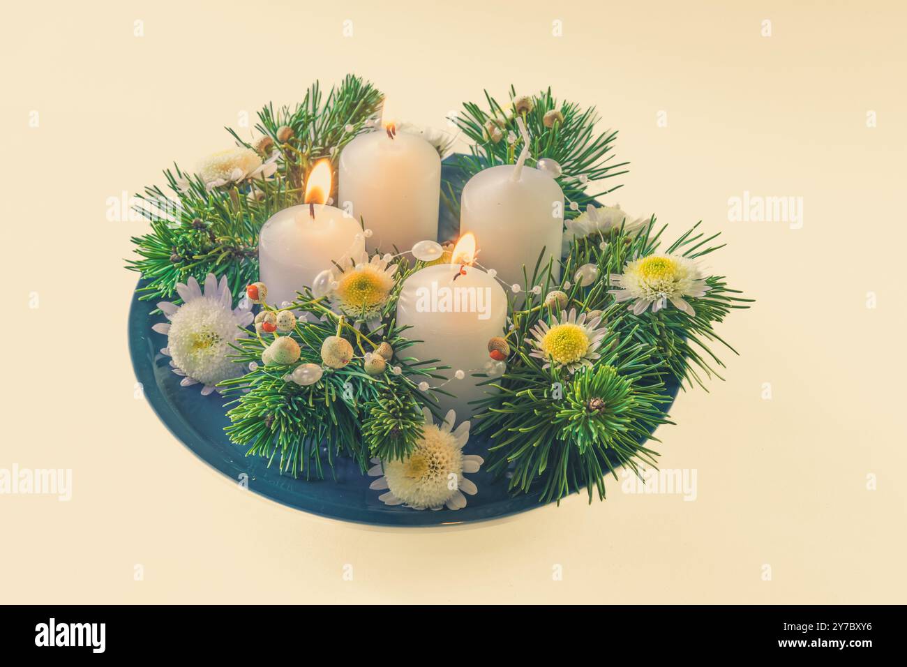 quattro candele bianche dell'avvento, decorazioni a corona con fiori e pino, isolate, candele del secondo avvento accese Foto Stock