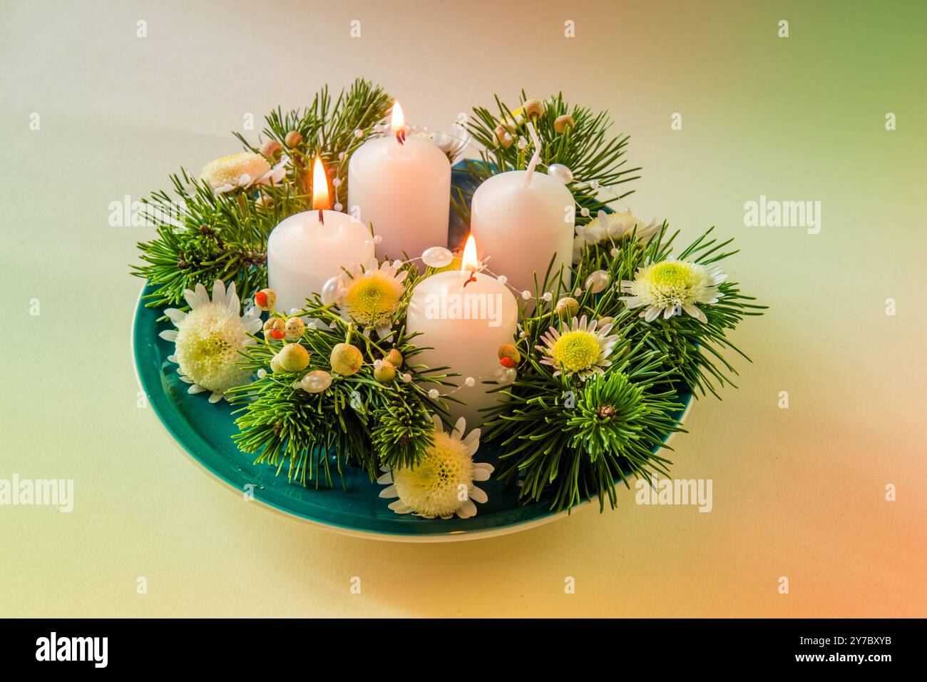 quattro candele bianche dell'avvento, decorazioni a corona con fiori e pino, isolate, tre candele dell'avvento accese Foto Stock
