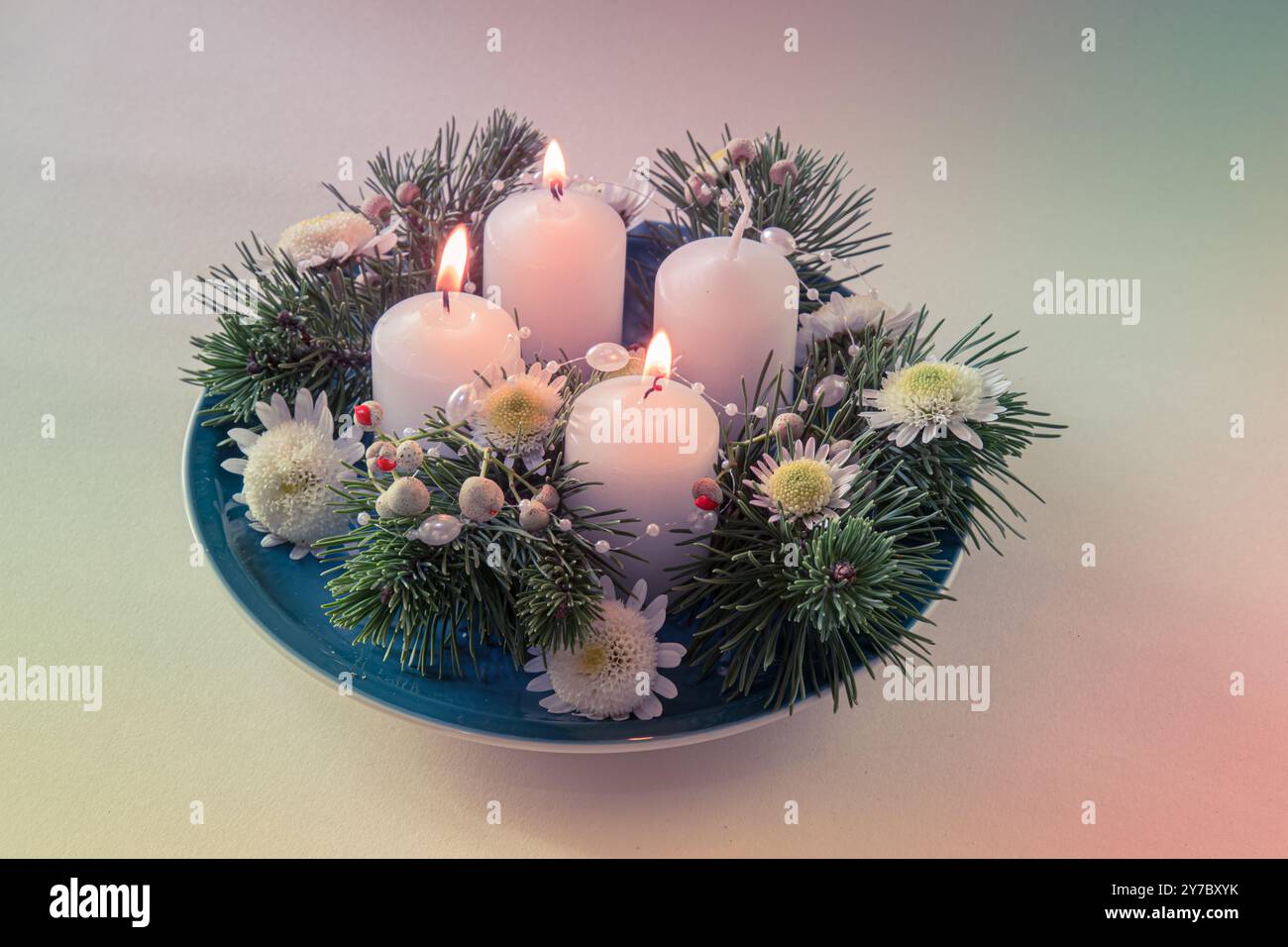 quattro candele bianche dell'avvento, decorazioni a corona con fiori e pino, isolate, tre candele dell'avvento accese Foto Stock