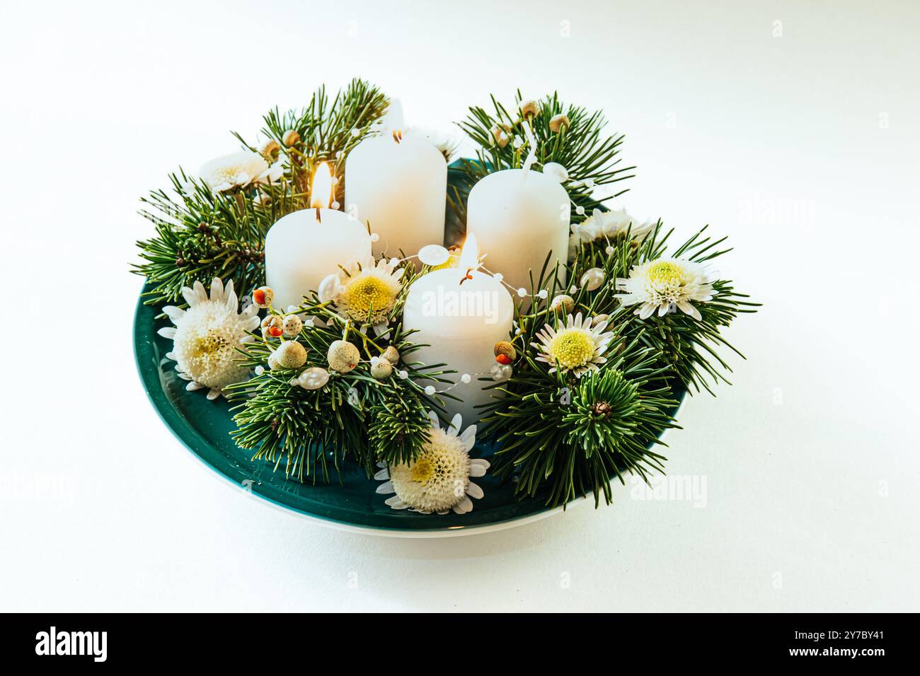 quattro candele bianche dell'avvento, decorazioni a corona con fiori e pino, isolate, tre candele dell'avvento accese Foto Stock