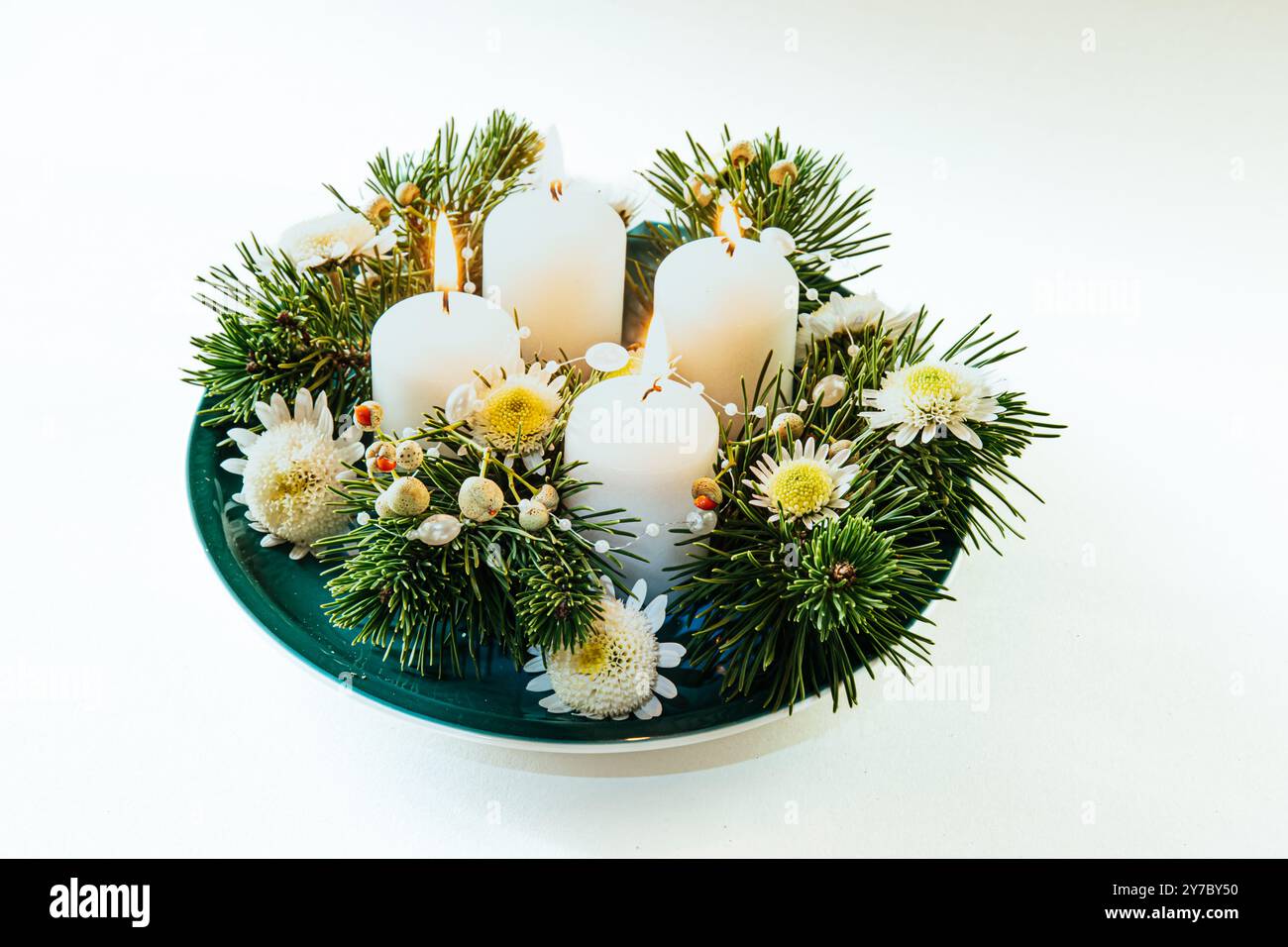 quattro candele bianche dell'avvento, decorazioni a corona con fiori e pini, isolate, quattro candele dell'avvento accese Foto Stock