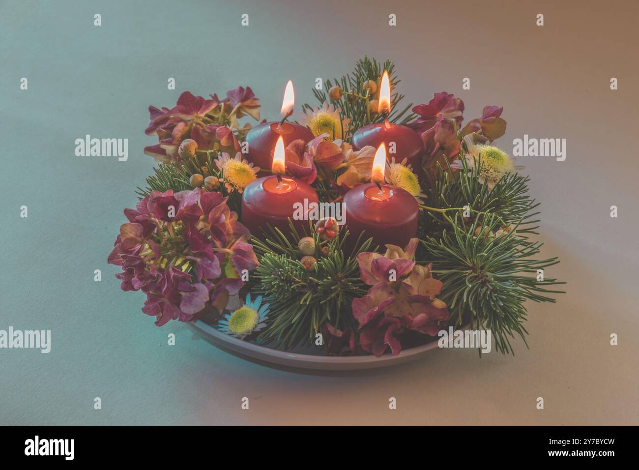 quattro candele bianche dell'avvento, decorazioni a corona con fiori e pini, isolate, quattro candele dell'avvento in fiamme Foto Stock