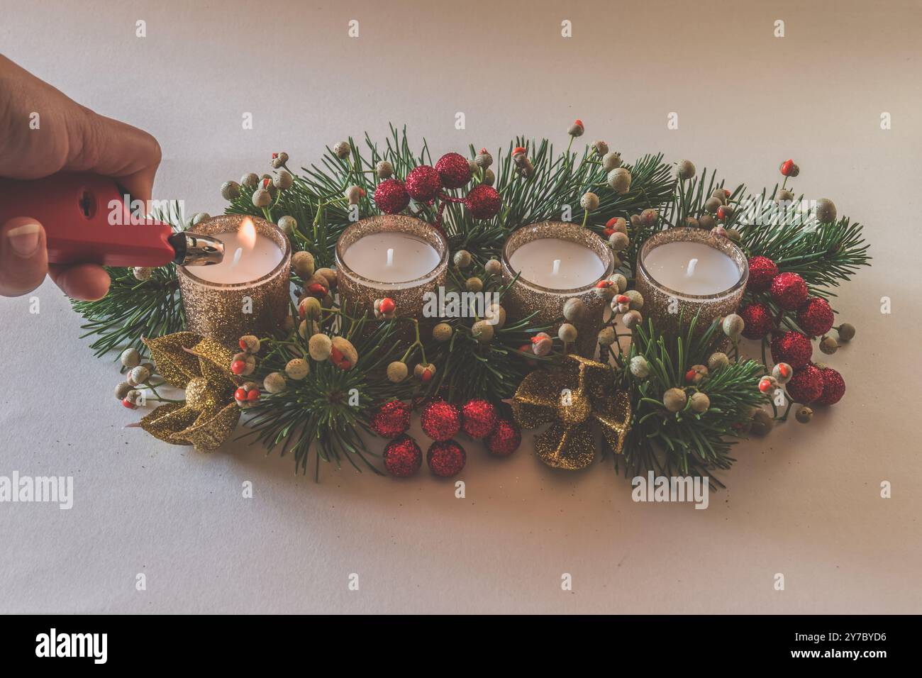quattro candele bianche dell'avvento, decorazioni a corona con fiori e pini, isolate, una candela dell'avvento bruciata Foto Stock