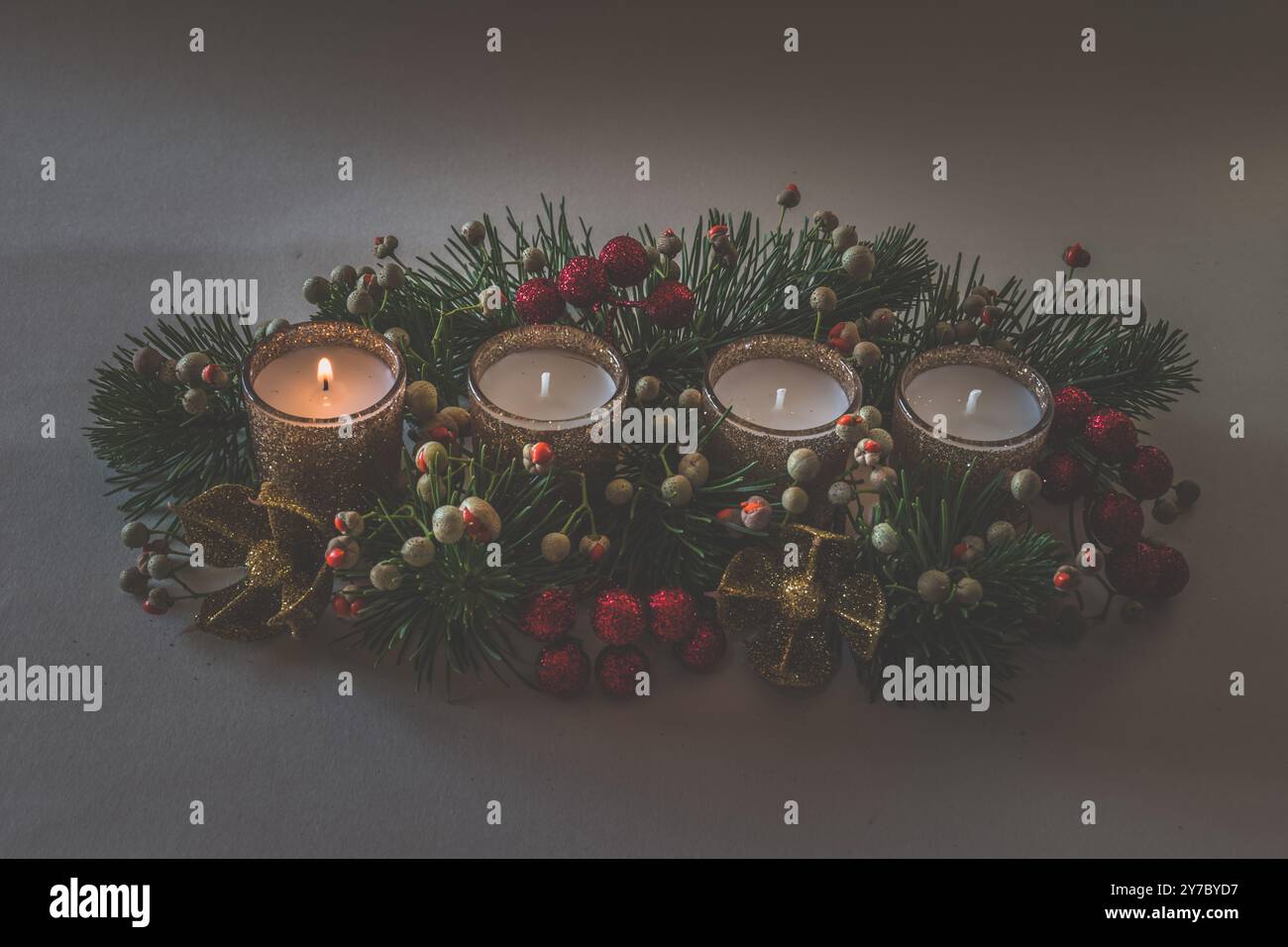 quattro candele bianche dell'avvento, decorazioni a corona con fiori e pini, isolate, una candela dell'avvento bruciata Foto Stock