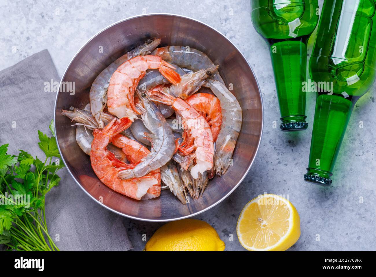 Gamberetti crudi freschi, accompagnati da rametti di prezzemolo fresco e limone succoso, pronti per la cottura. Spuntino con birra ideale Foto Stock