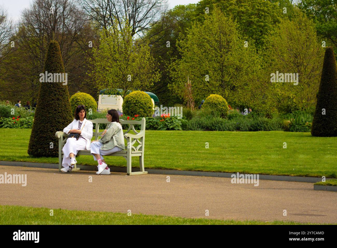 Londra, Inghilterra, aprile 30 2023: Due signore sedute su una panchina nei Kensington Gardens si godono una giornata estiva Foto Stock