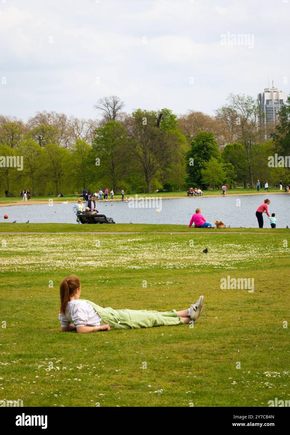 Londra, Inghilterra, aprile 30 2023: Donna sdraiata nell'erba di Kensington Gardens in una bella giornata Foto Stock
