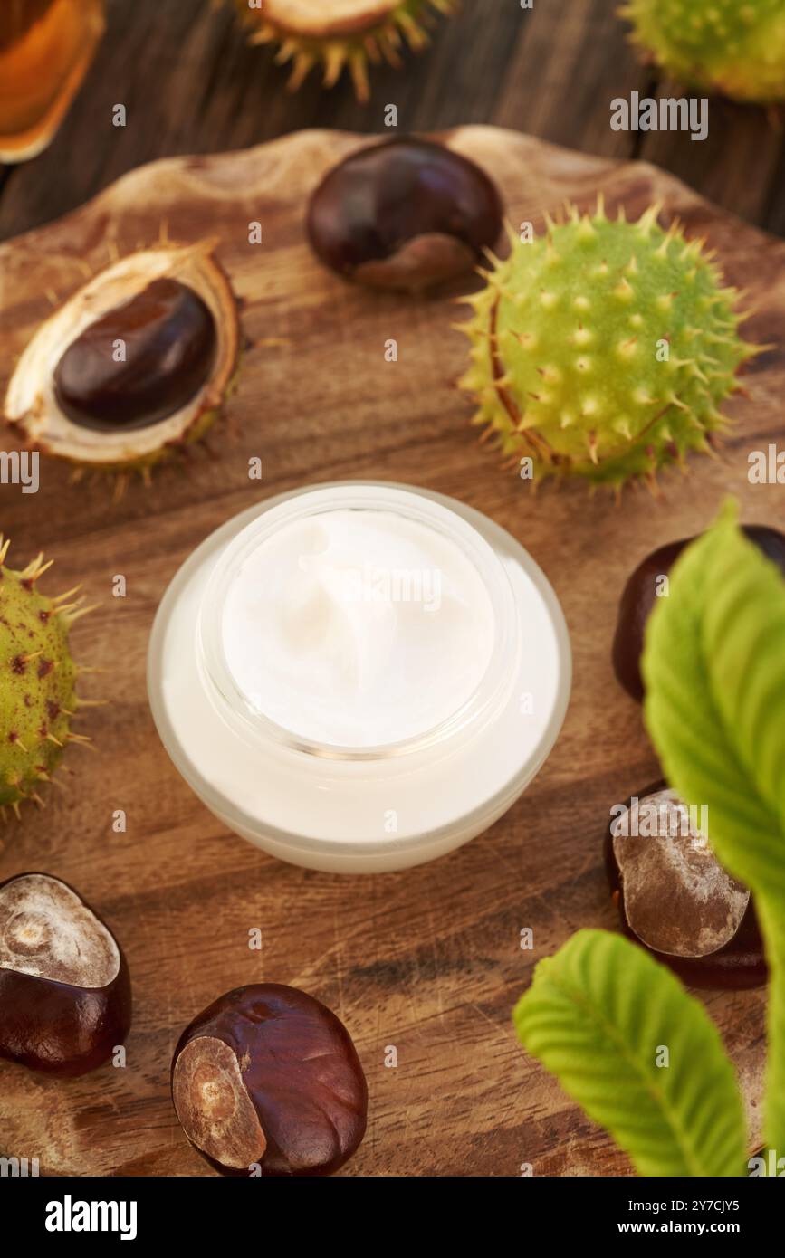 Crema di castagne o unguento in un vaso di vetro su un tavolo di legno Foto Stock