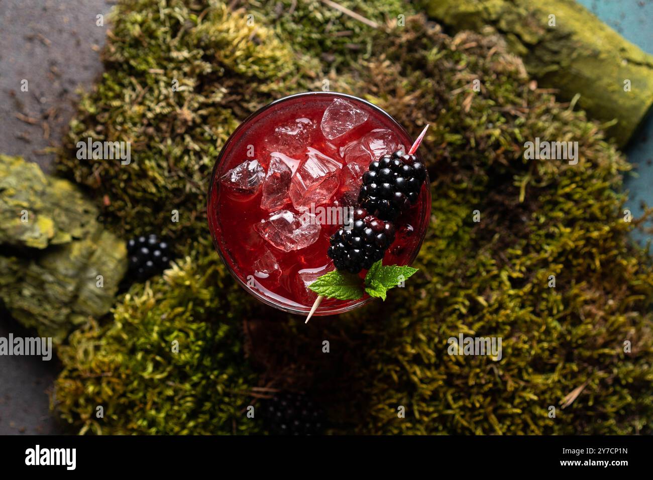 Limonata fredda di frutti di bosco con ghiaccio per una giornata calda. Con uno sfondo di legno e muschio. Foto Stock