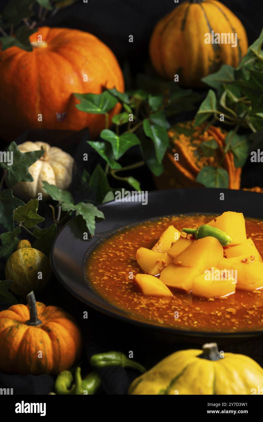 Un piatto di gulasch con zucche e foglie verdi in un'atmosfera autunnale, cibo di Halloween Foto Stock
