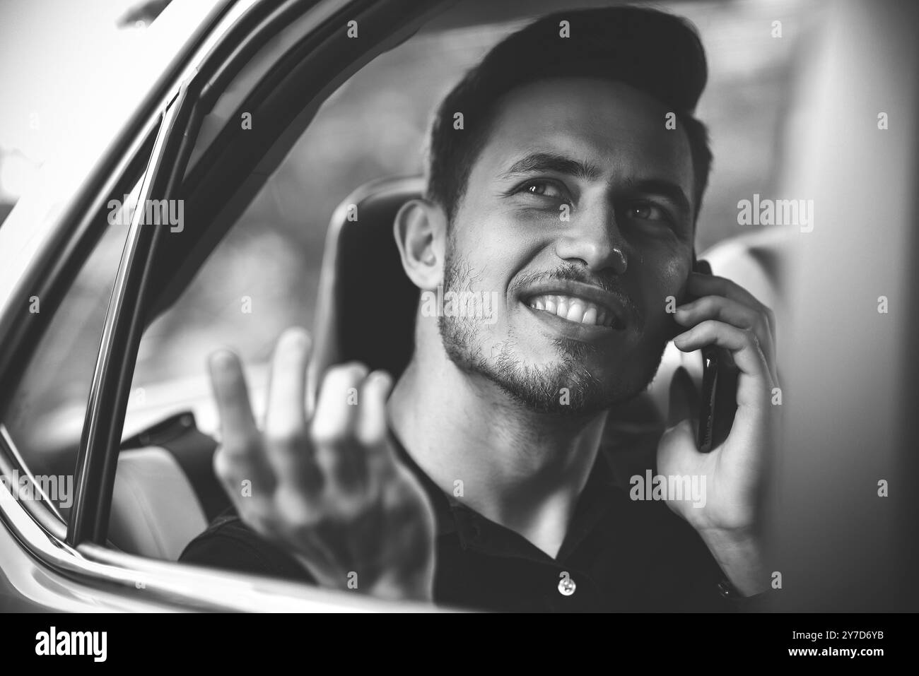 Bell'uomo seduto sul sedile posteriore dell'auto e usa un telefono Foto Stock