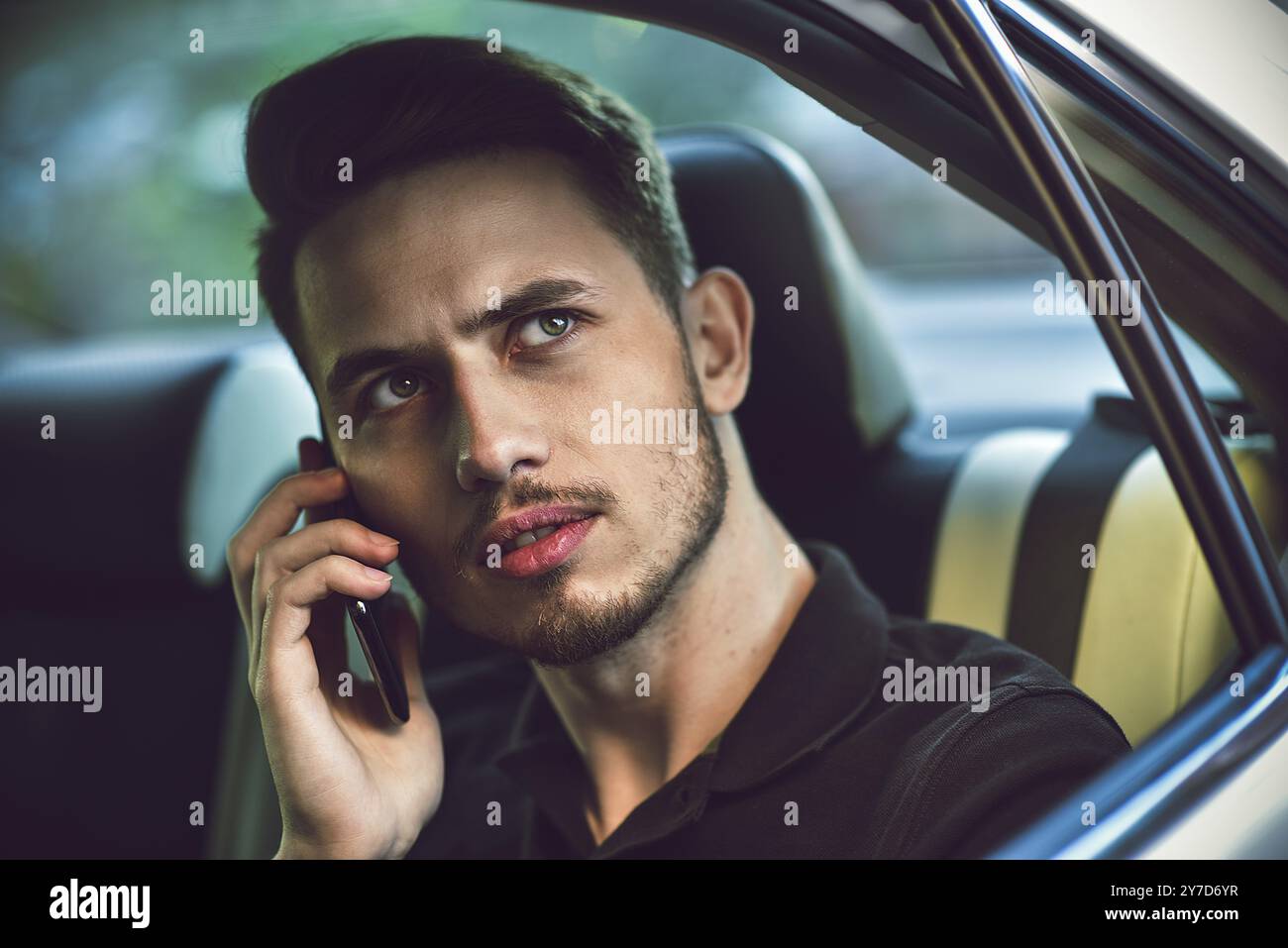 Bell'uomo seduto sul sedile posteriore dell'auto e usa un telefono Foto Stock