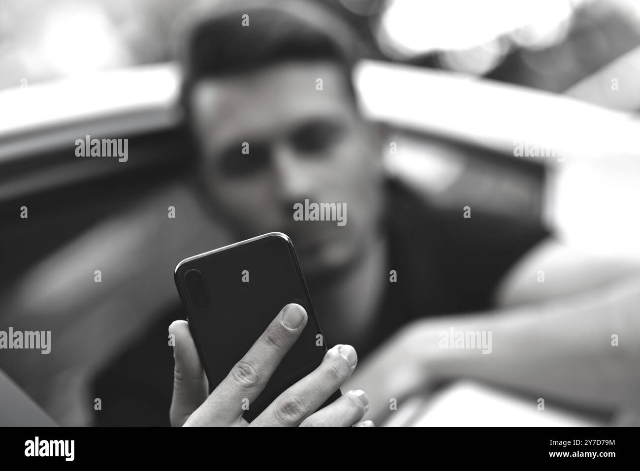Il viaggiatore d'affari utilizza uno smartphone sul sedile posteriore dell'auto Foto Stock