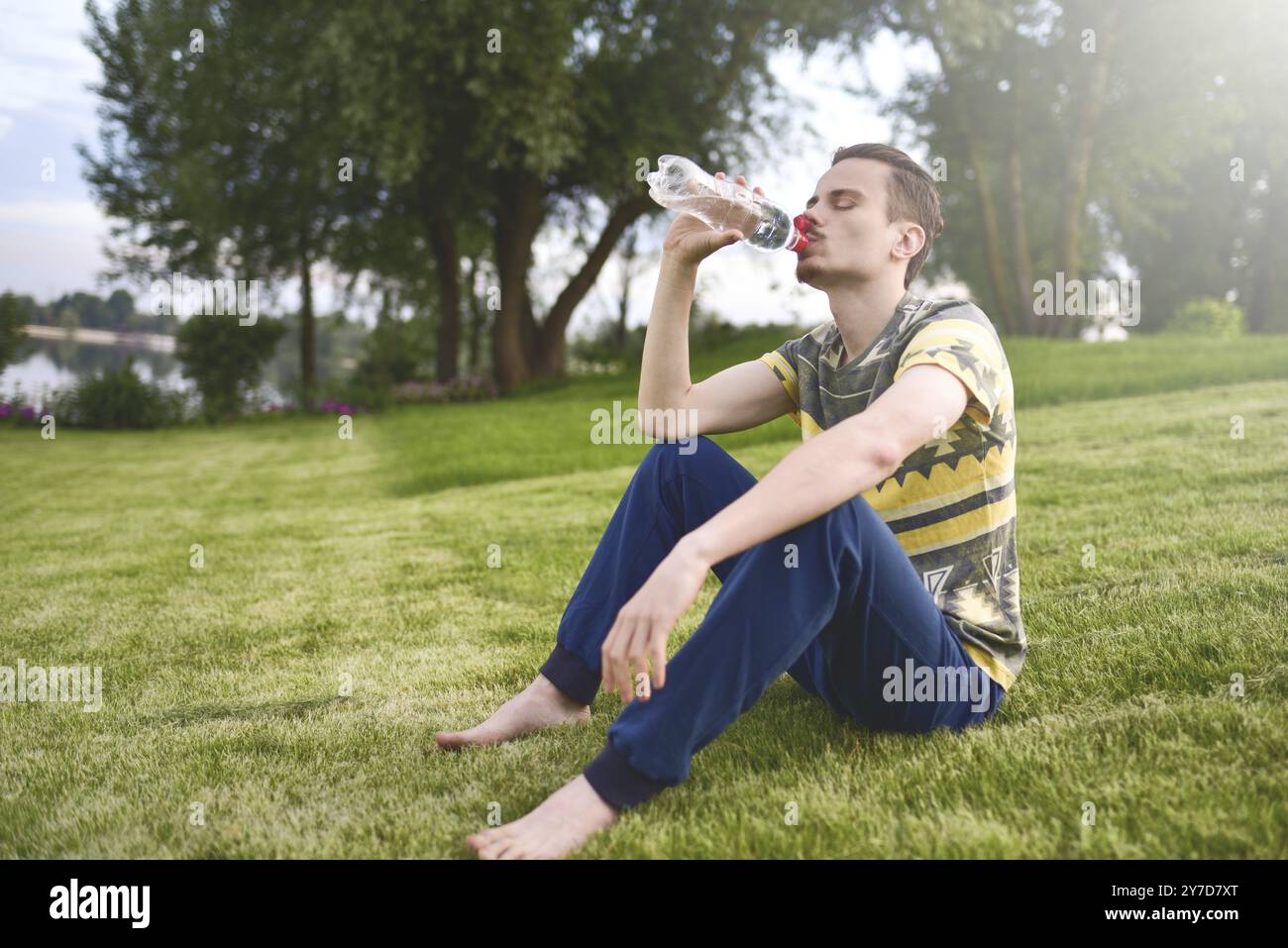 Giovane uomo seduto sul giardino e acqua potabile dopo l'esecuzione Foto Stock