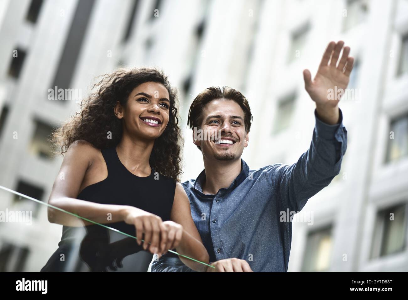 Una felice coppia internazionale ha una conversazione in città. Donna di razza mista e uomo caucasico Foto Stock