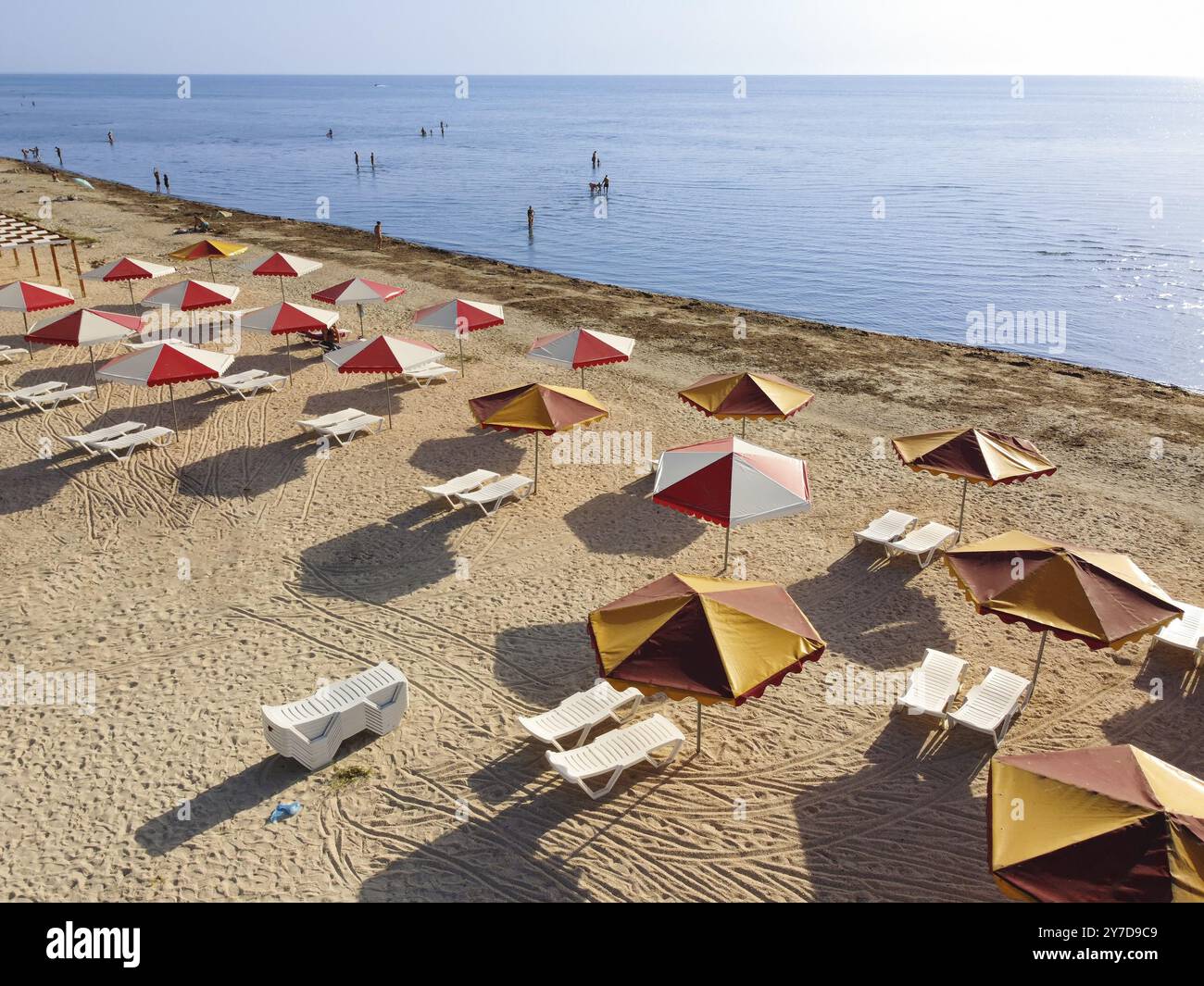 Spiaggia con ombrelloni e mare sporco che porta molte alghe alla riva Foto Stock