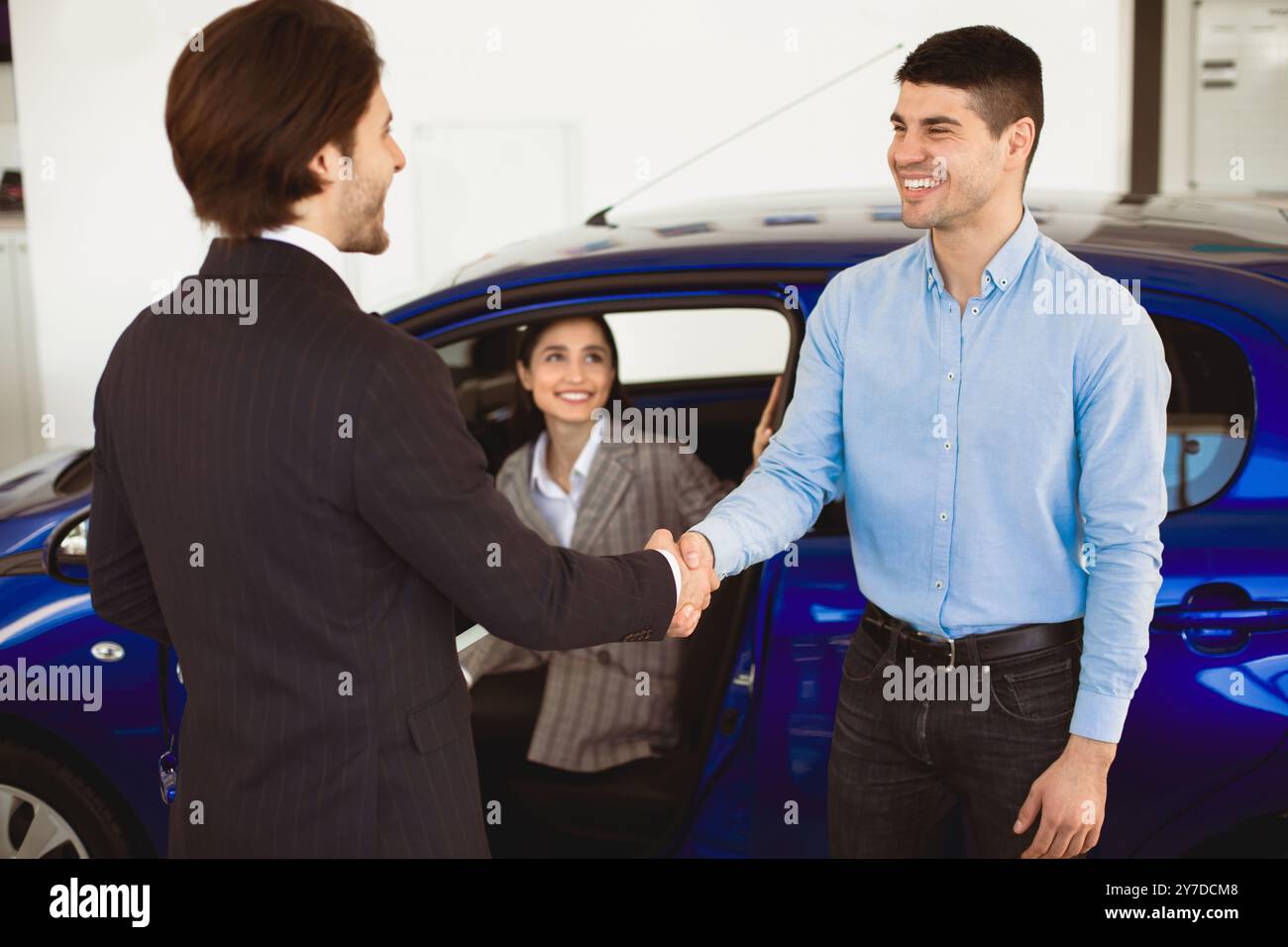 Uomo Che Si Stringe Le Mani Con Il Responsabile Delle Vendite Di Auto Nel Dealership Store Foto Stock