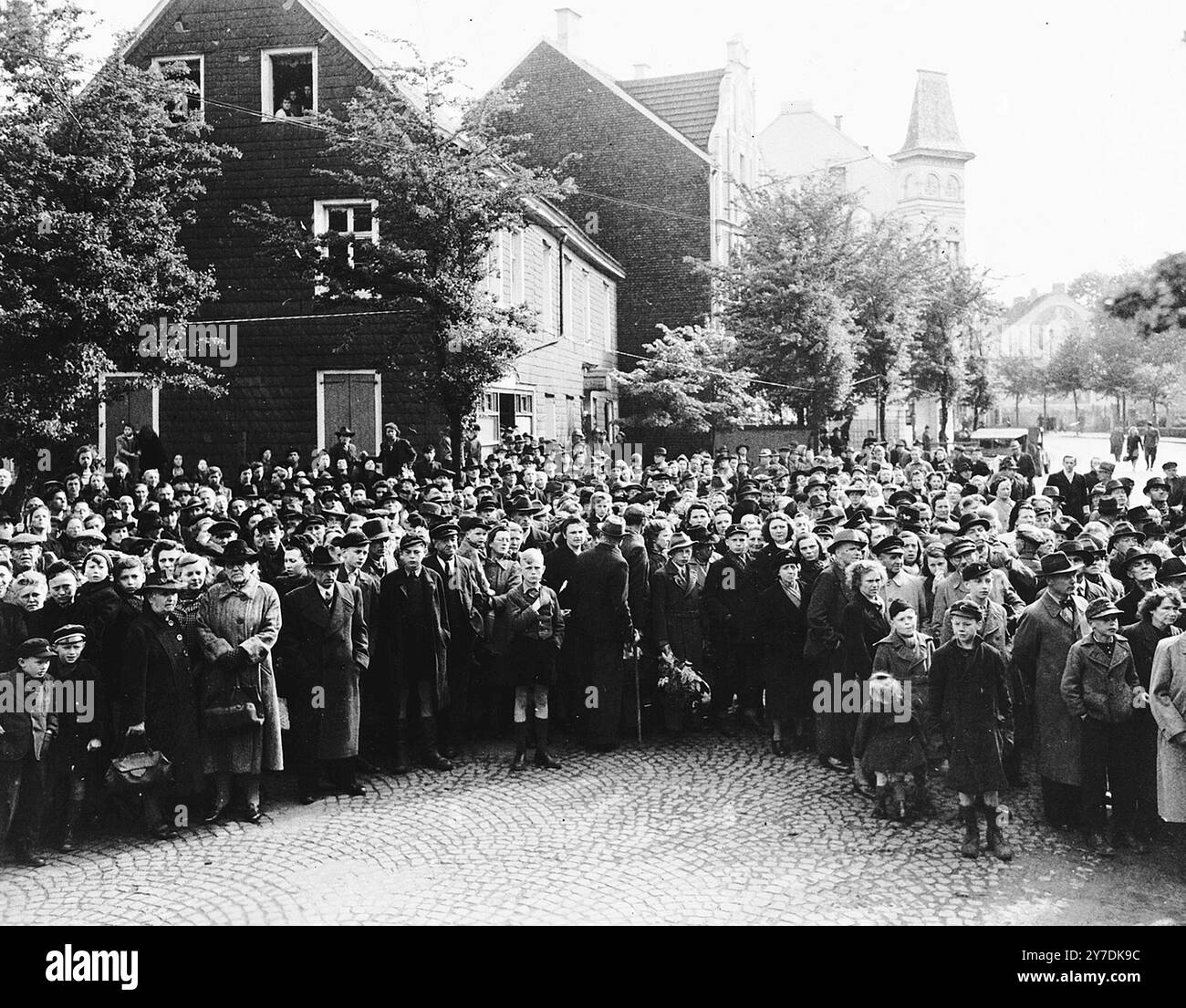 I civili tedeschi assistono ai funerali per i 71 prigionieri politici, riesumati da una tomba comune vicino a Solingen-Ohligs, risepolti di fronte al municipio. Le vittime, la maggior parte delle quali sono state prese dalla prigione di Luettringhausen, sono state uccise e sepolte dalla Gestapo seguendo l'ordine di eliminare tutti i nemici del Reich poco prima della fine della guerra. Azioni come questa facevano parte del processo di denazificazione. Questo processo fu un tentativo di liberare la cultura e la società tedesca e austriaca dall'influenza e dall'ideologia nazista. Una parte del processo includeva il confronto con il pubblico con le prove dei crimini che erano stati commessi Foto Stock