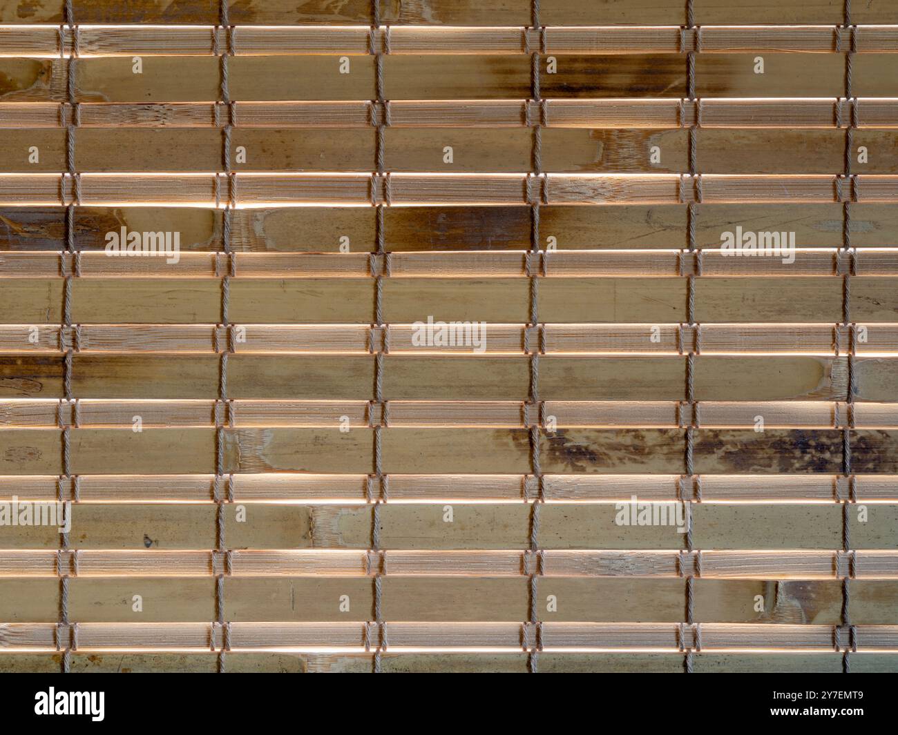 La luce del sole splende attraverso le lamelle di una tenda di bambù Foto Stock
