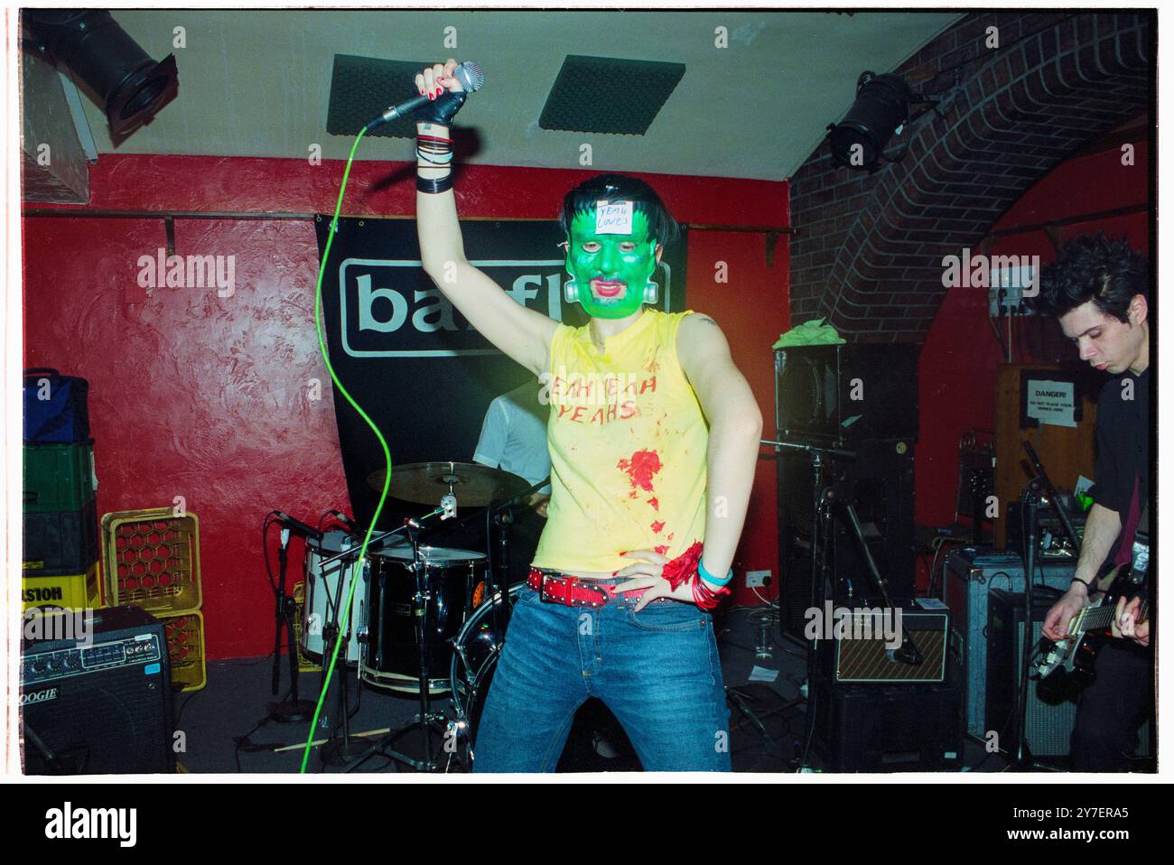 KAREN o, YEAH YEAH YEAHS, PRIMO TOUR nel Regno Unito, 2002: A Young Karen o of Yeah Yeah Yeahs si esibisce in un film horror Frankenstein mask suonando un piccolo concerto sudato nel loro primo tour nel Regno Unito al Barfly Club di Cardiff, Galles, Regno Unito, il 21 aprile 2002. Foto: Rob Watkins. NFO: Yeah Yeah Yeahs è un gruppo musicale indie rock statunitense formatosi nel 2000, noto per il loro energico sound art-punk. Guidati dalla carismatica cantante Karen o, hanno guadagnato fama con successi come "Maps" e "Heads Will Roll", che fondono il rock grezzo del garage con la profondità emotiva. Foto Stock