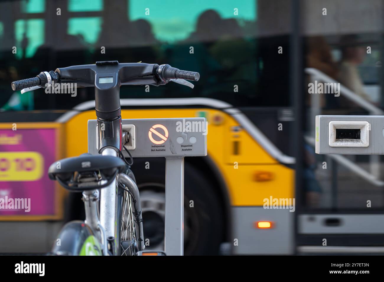 Lisbona, Portogallo - 10 settembre 2024 : Una bicicletta è custodita in un portabiciclette vicino a un autobus giallo che mostra informazioni sull'accessibilità. Foto Stock