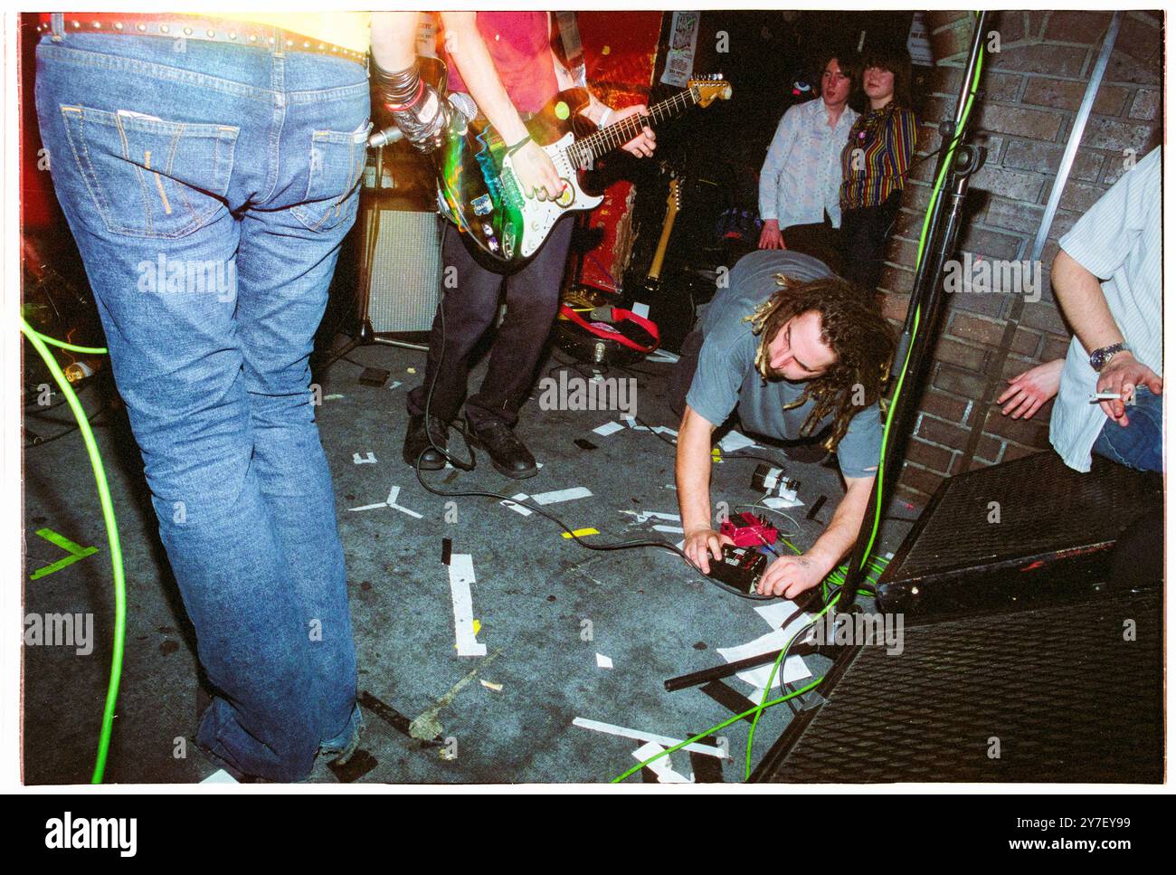 KAREN o, YEAH YEAH YEAHS, PRIMO TOUR nel Regno Unito, 2000: Il roadie Yeah Yeah Yeah Yeahs fa alcune riparazioni durante un piccolo concerto sudato nel loro primo tour nel Regno Unito al Barfly Club di Cardiff, Galles, Regno Unito, il 21 aprile 2002. Foto: Rob Watkins. NFO: Yeah Yeah Yeahs è un gruppo musicale indie rock statunitense formatosi nel 2002, noto per il loro energico sound art-punk. Guidati dalla carismatica cantante Karen o, hanno guadagnato fama con successi come "Maps" e "Heads Will Roll", che fondono il rock grezzo del garage con la profondità emotiva. Foto Stock