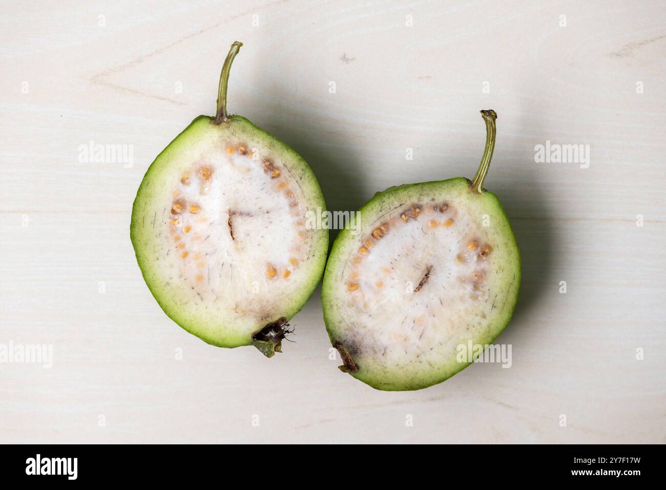 Una guava fresca tagliata in due pezzi, rivelando il suo interno succoso. La guava è un frutto tropicale gustoso e salutare. Vista dall'alto. Foto Stock