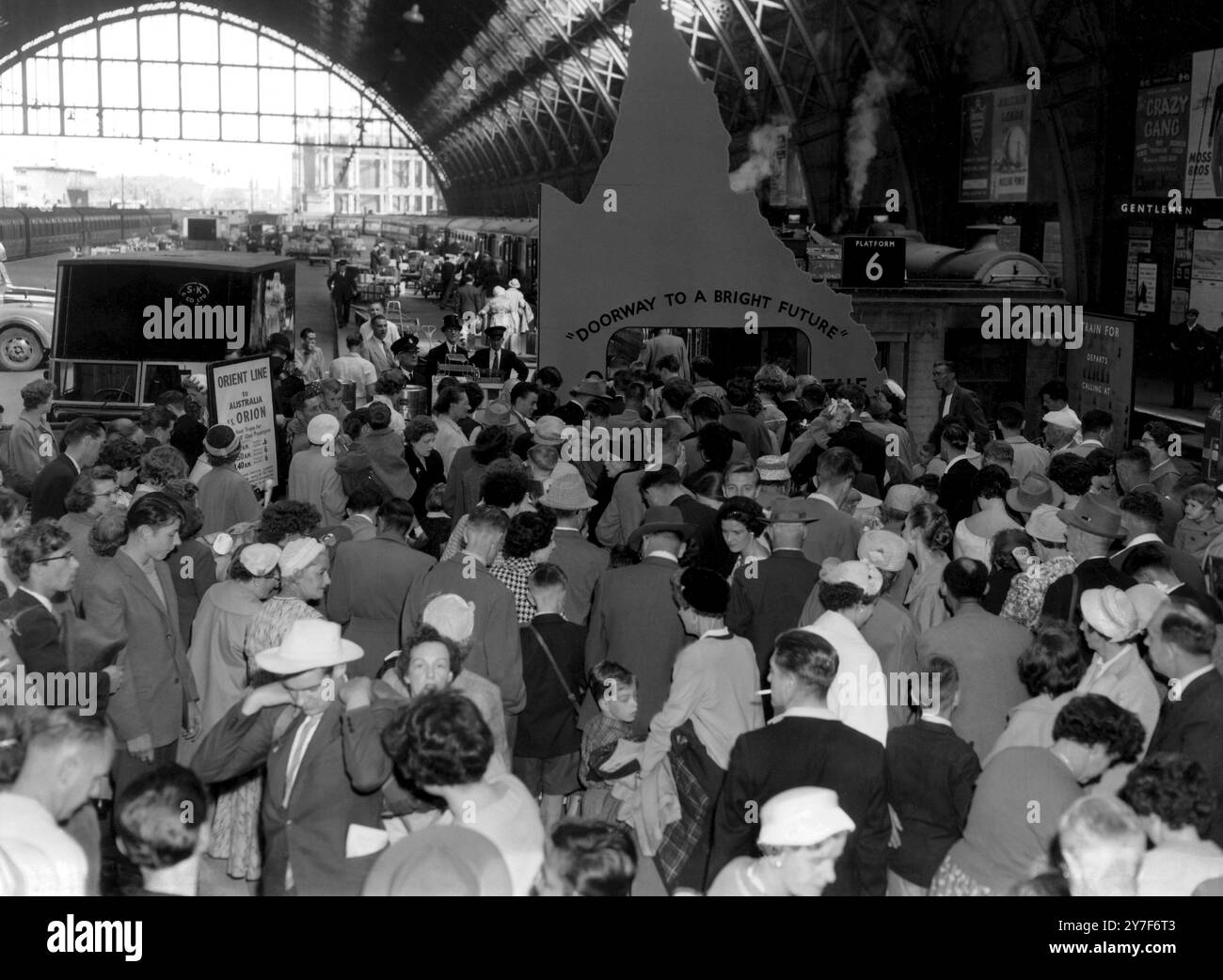 I britannici sono "regalo di compleanno"! La scena affollata di St Pancras, Londra, come gruppo di 437 inglesi partì per la prima tappa del loro viaggio a Brisbane, Australia. I migranti salperanno questo pomeriggio da Tilbury nell'Orion, che sta facendo un viaggio speciale a Brisbane per le celebrazioni del 100° compleanno dello stato del Queensland. Un cartello alla stazione li salutava con le parole "Doorway to a Bright Future" e le ragazze australiane gli davano dei bicchieri di succo di ananas del Queensland. 19 luglio 1959 Foto Stock