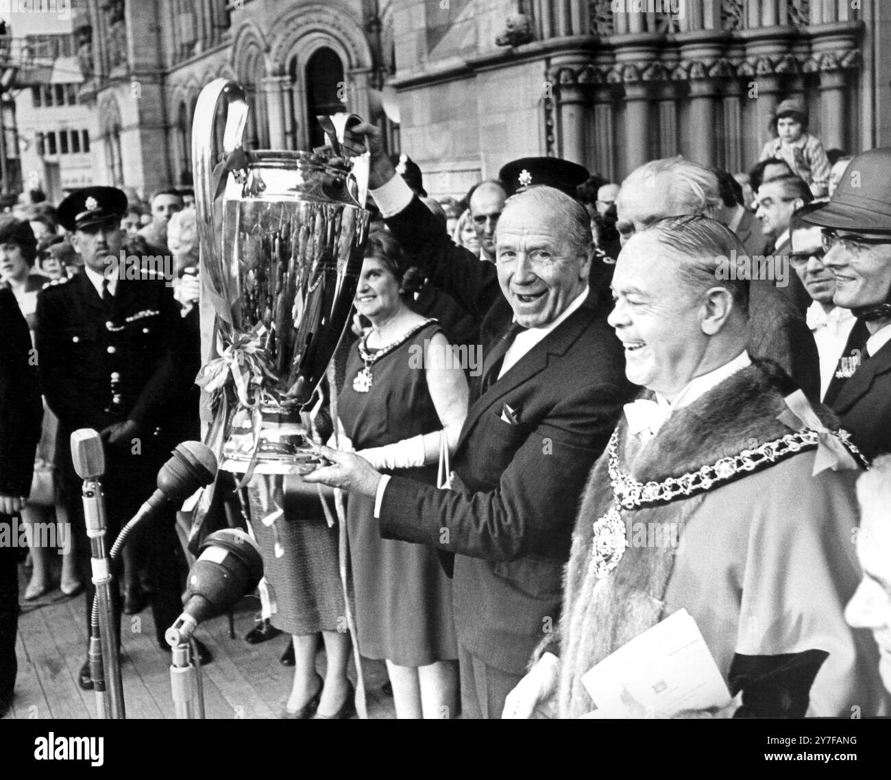 L'allenatore del Manchester United Matt Busby tiene in alto la Coppa dei campioni europei al saluto delle folle tifose fuori dal municipio di Manchester, quando i campioni d'Europa tornarono a casa in trionfo. A destra c'è il sindaco Harold Stockdale. 30 maggio 1968. Foto Stock