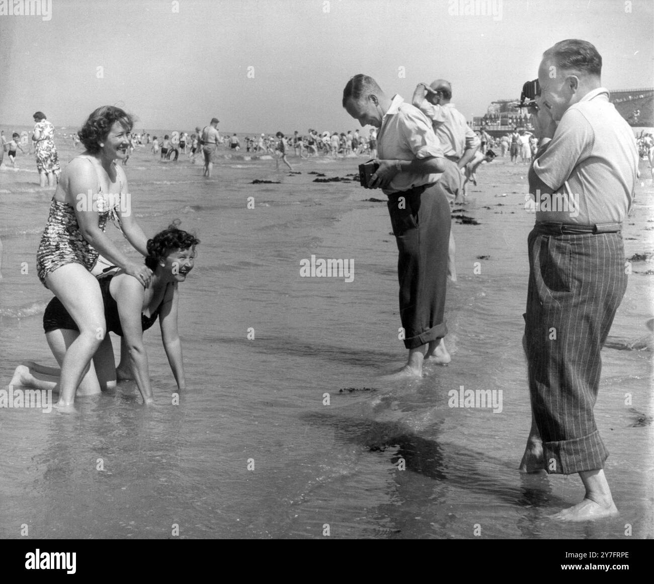 uomini con macchine fotografiche (brownies in scatola? rolleiflex?) fotografare le mogli che giocano sulla spiaggia Foto Stock
