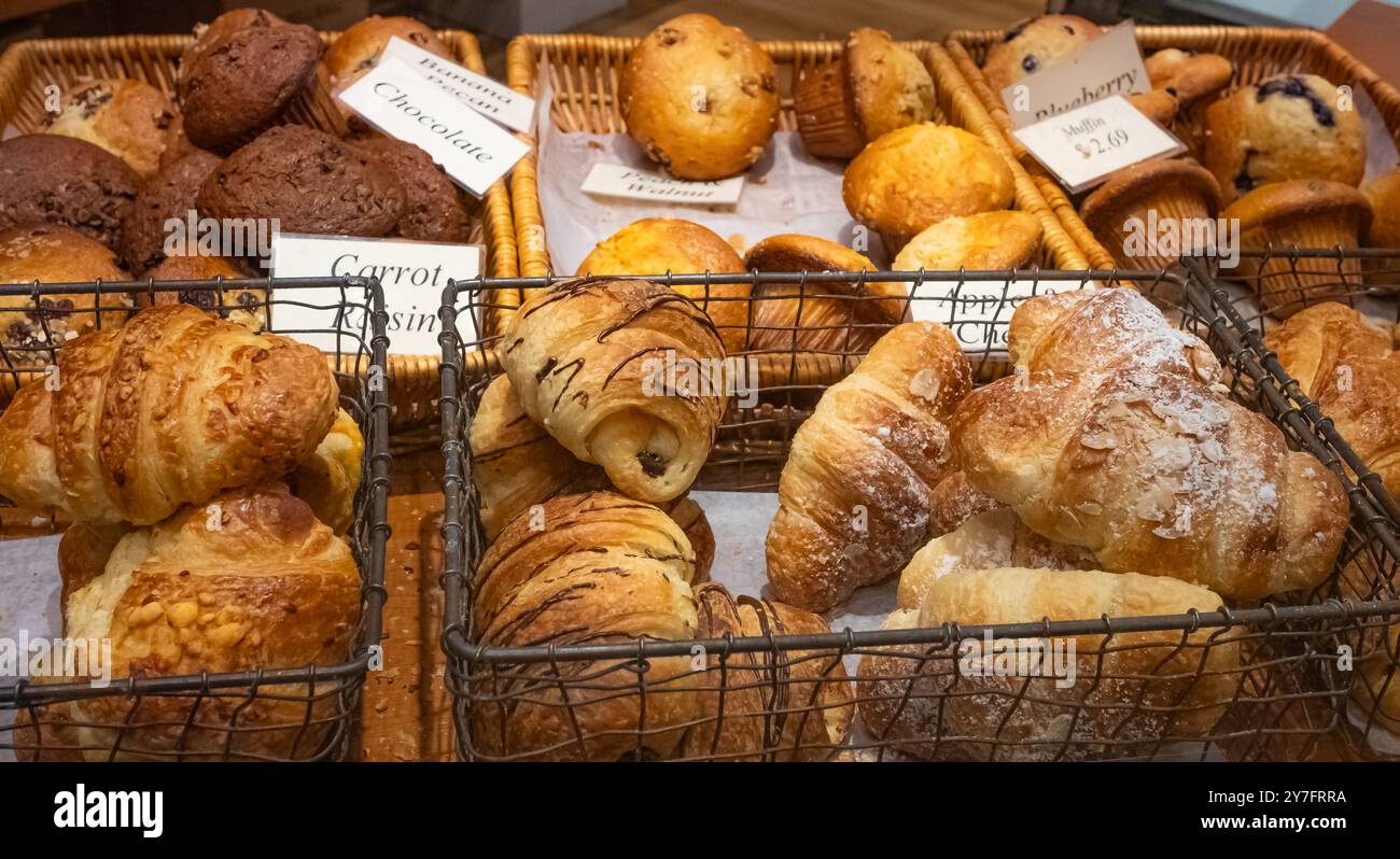 Bistrot con scaffali di croissant freschi. Pasticceria assortita disposta su vassoio venduta in una panetteria. Primo piano di appetitosi croissant dorati Foto Stock