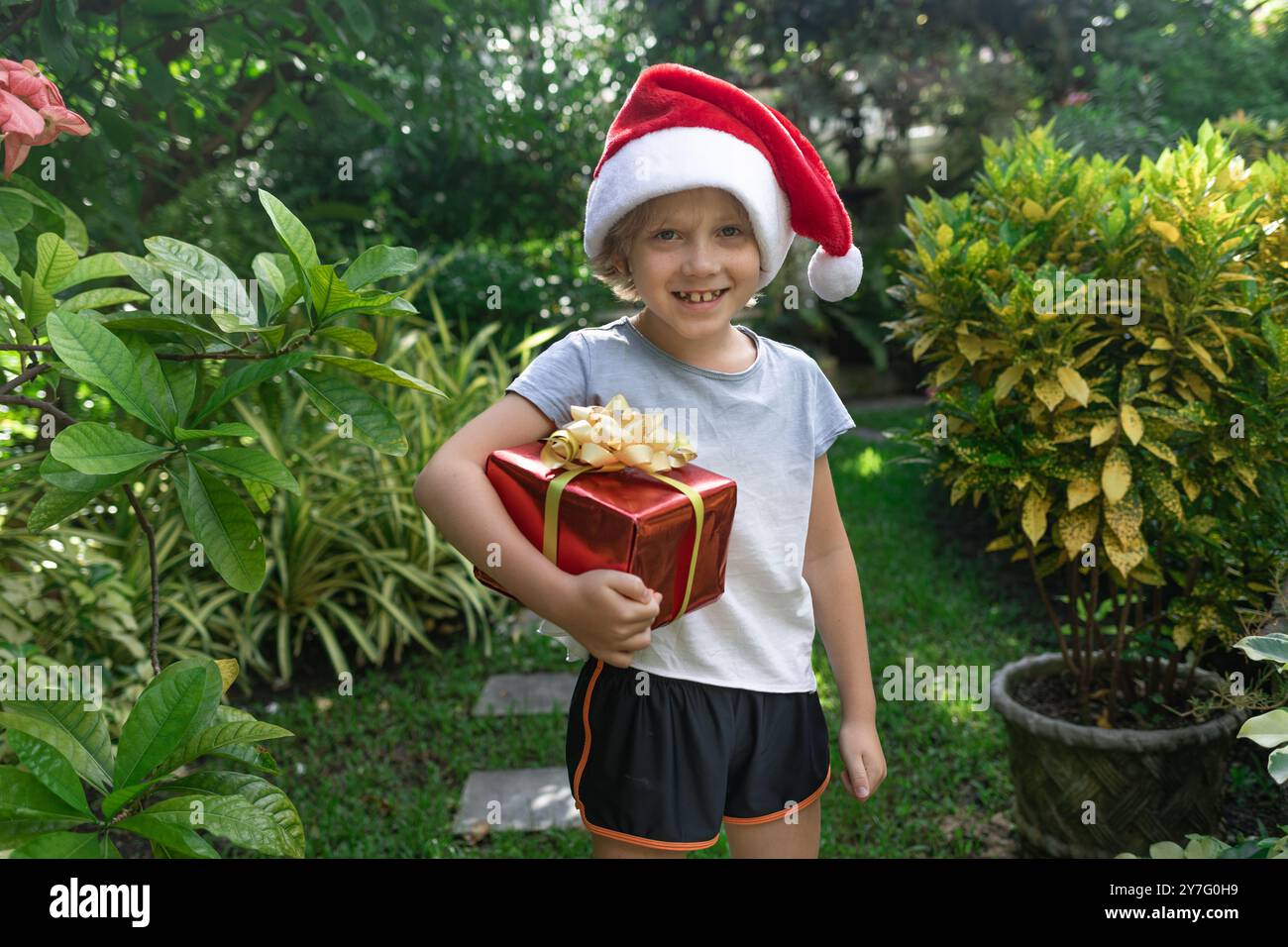 Bambino in cappello rosso di Babbo Natale con regalo, concept vacanza di Capodanno Foto Stock