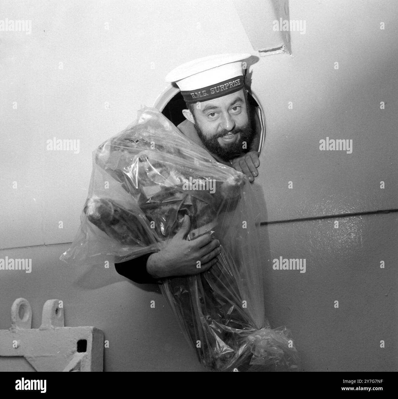 REM PAYNE WACKER GUARDA ATTRAVERSO L'OBLÒ SULLA HMS SURPRISE A PORTSMOUTH / ; 14 DICEMBRE 1964 Foto Stock