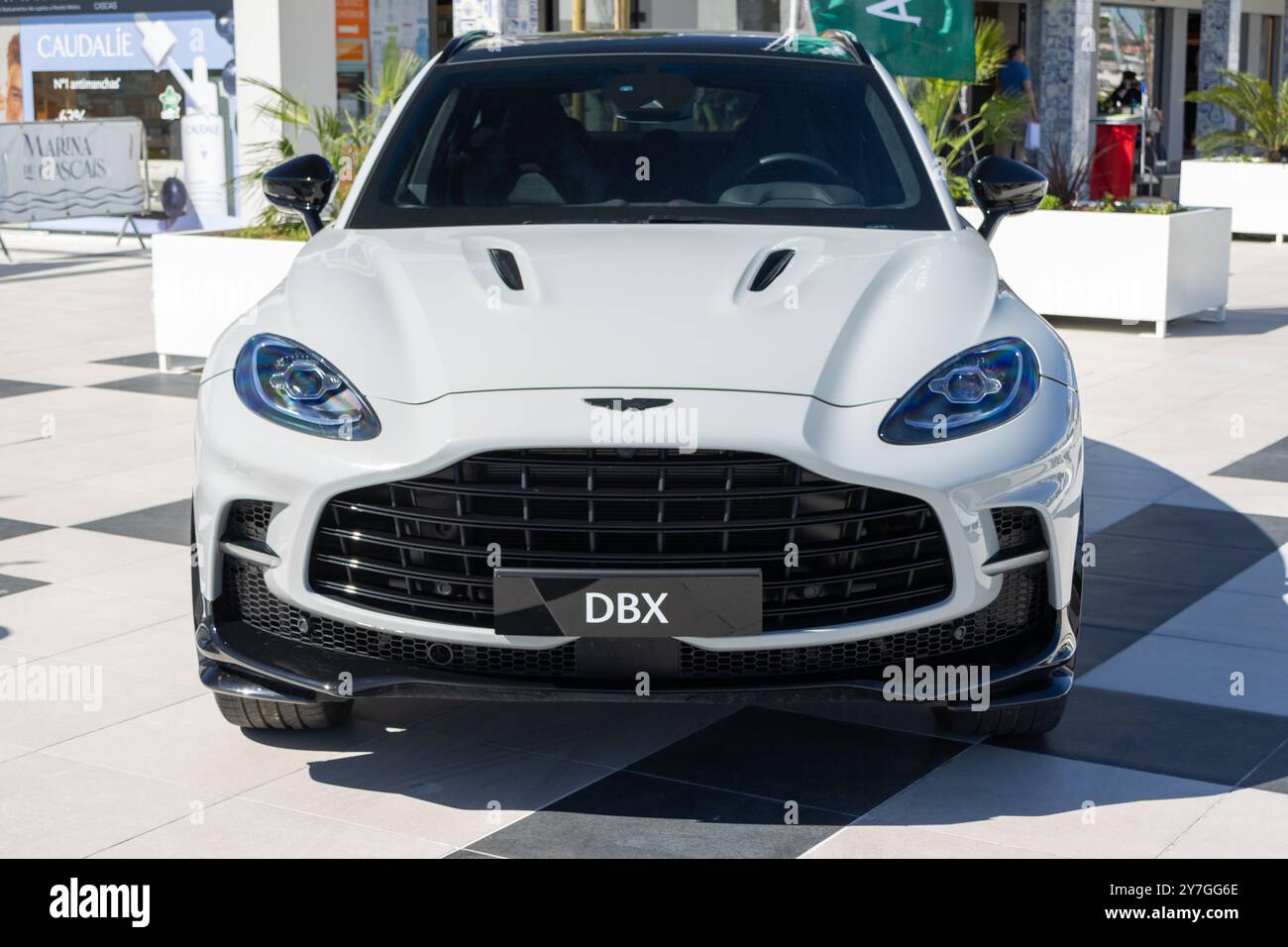 Vista frontale di un suv aston martin dbx bianco parcheggiato su un motivo a scacchi, che mostra il suo design lussuoso Foto Stock