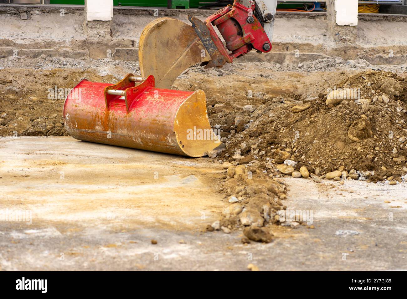 La benna dell'escavatore raccoglie il terreno e l'asfalto vecchio in un cantiere edile. Foto Stock