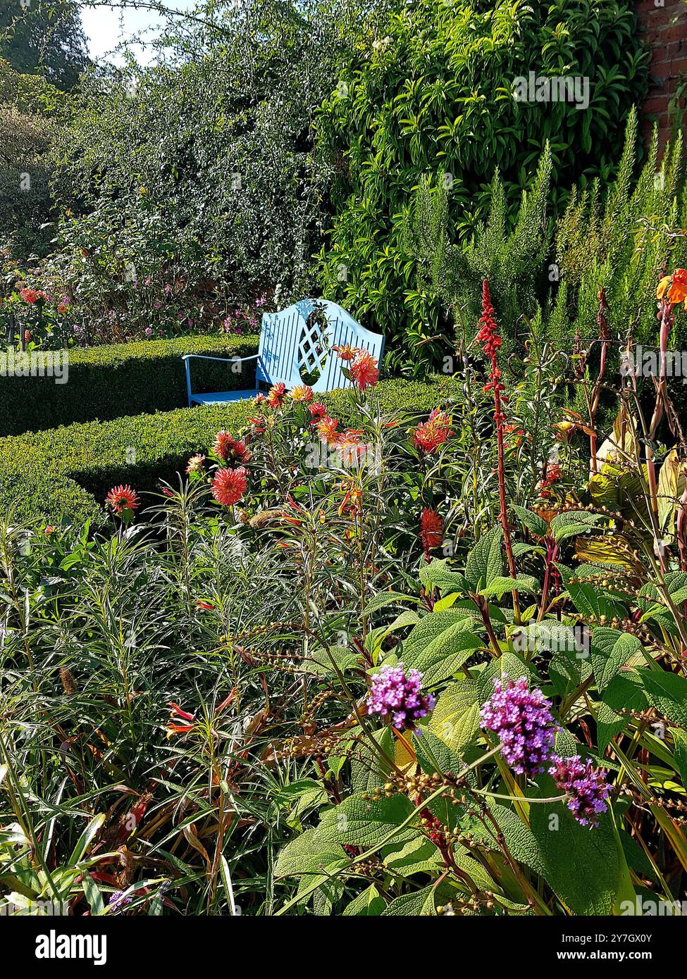 Un posto a sedere in giardino e fiori colorati in piena fioritura. Foto Stock