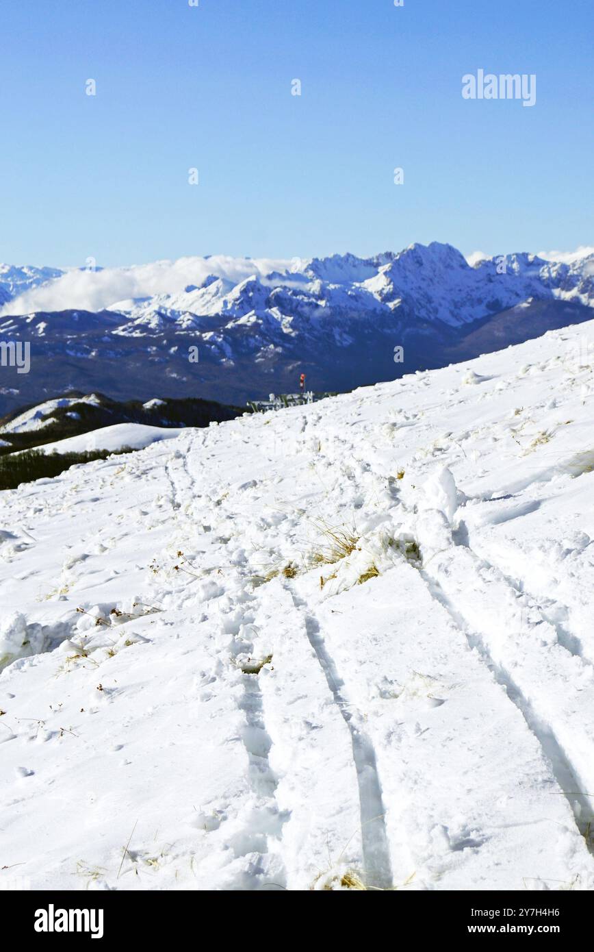 Vacanze attive nel nord del Montenegro: Paesaggio invernale di una stazione sciistica vicino a Kolasin. Pista con piste per motoslitte e montagne innevate Foto Stock