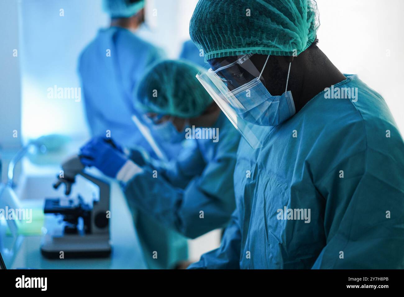 Lavoratori medici in tuta hazmat che lavorano con microscopio all'interno dell'ospedale di laboratorio durante l'epidemia di pandemia indossando maschere di sicurezza - Focus su african ma Foto Stock